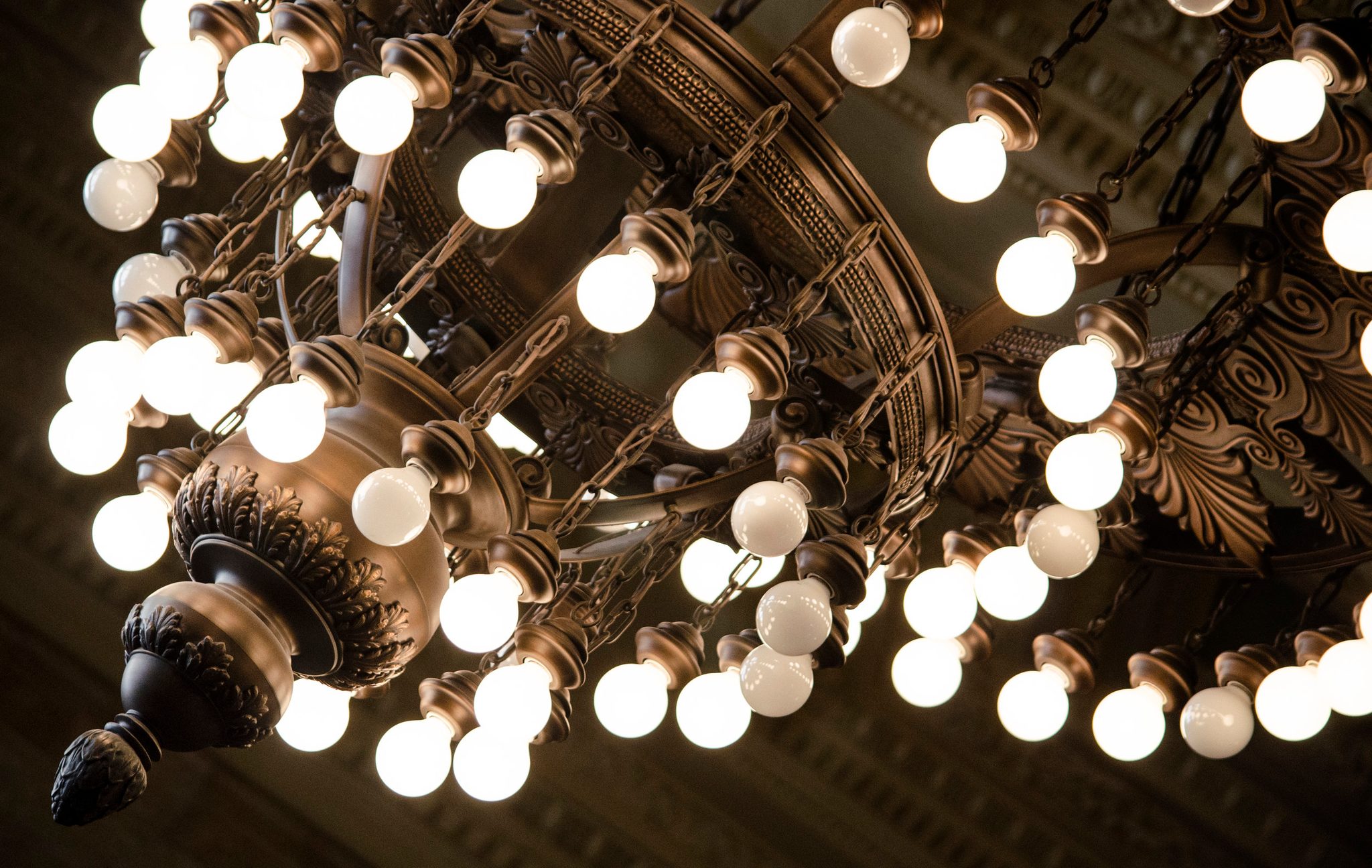 A chandelier blazes with rows of round bulbs.