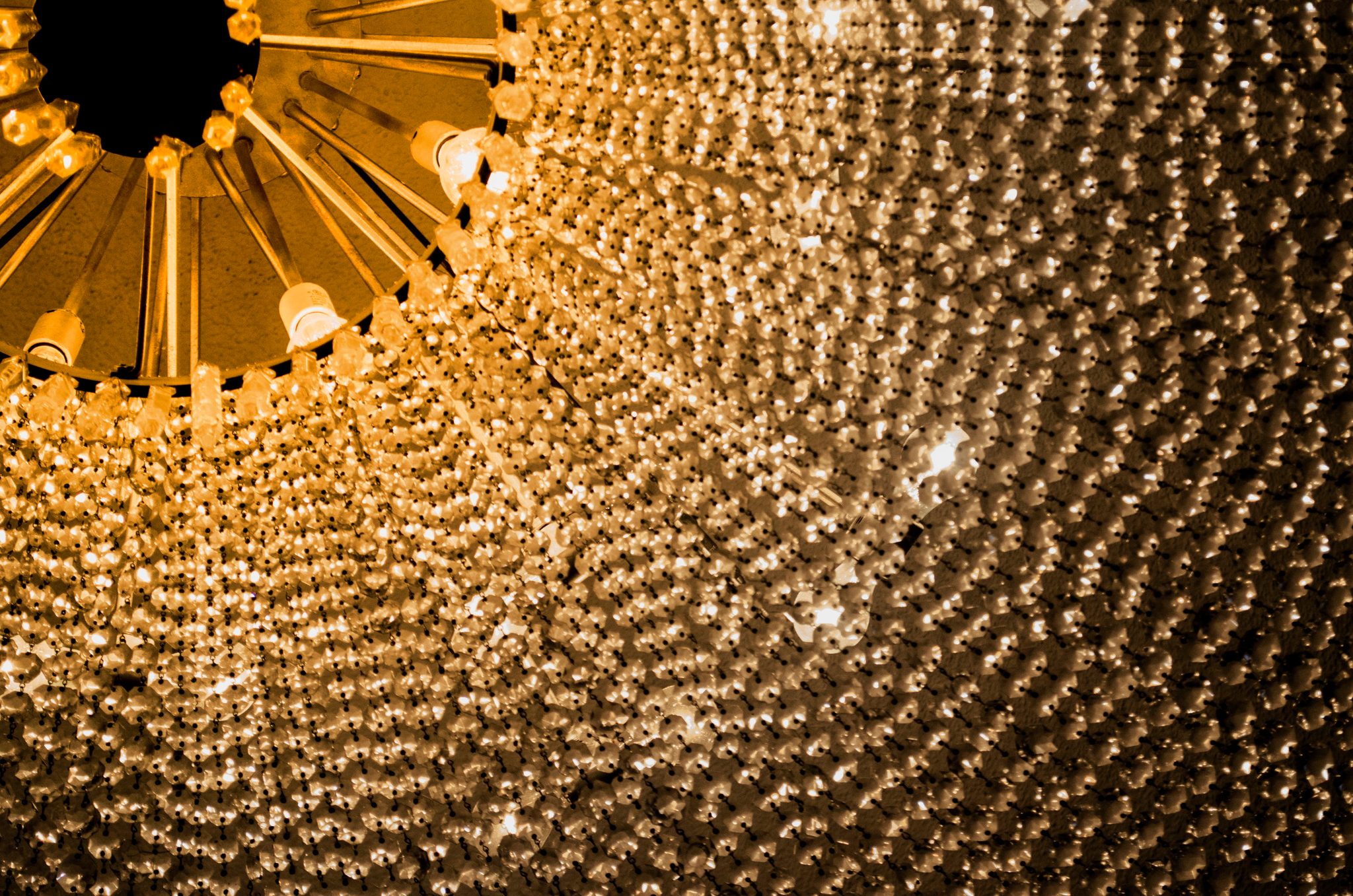 A chandelier drips with a thousand crystals like golden rain.