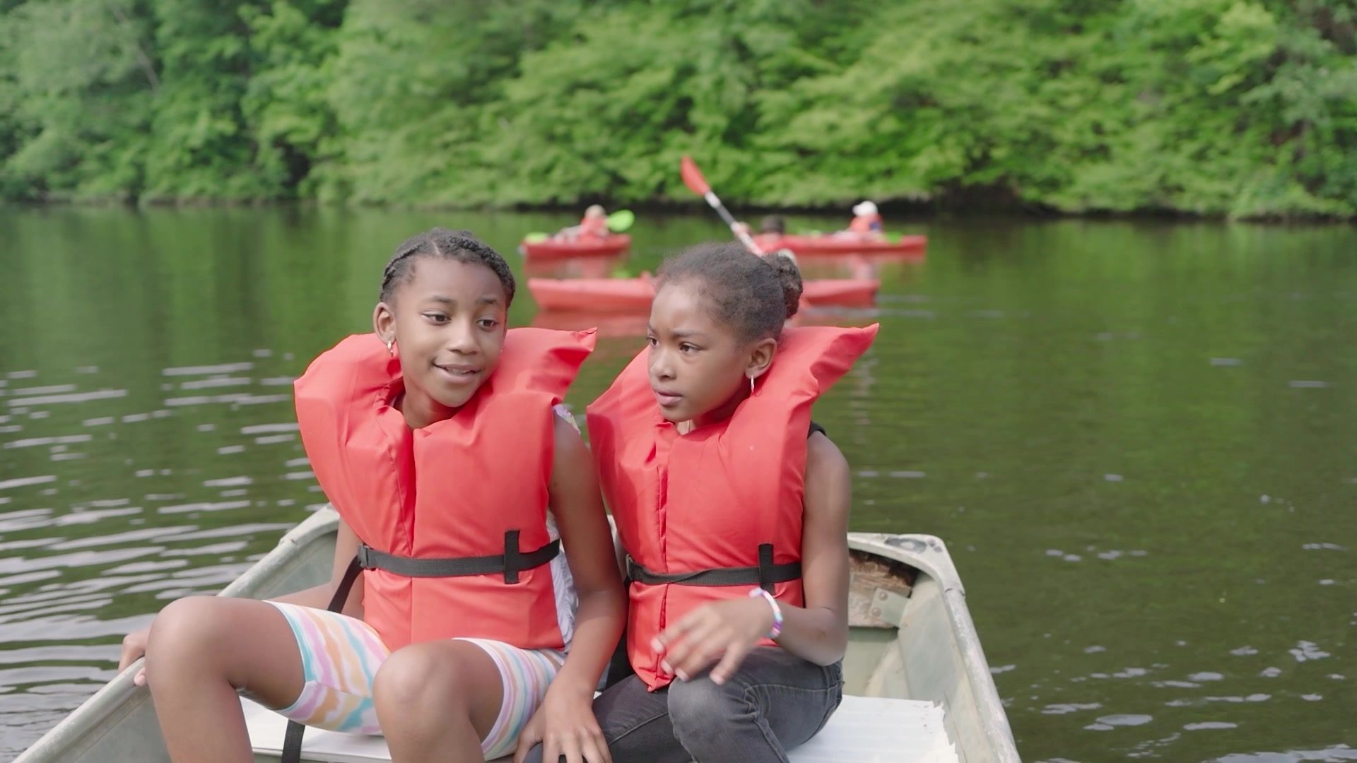 Two campers in life jackets wait in a rowboat on the lake.