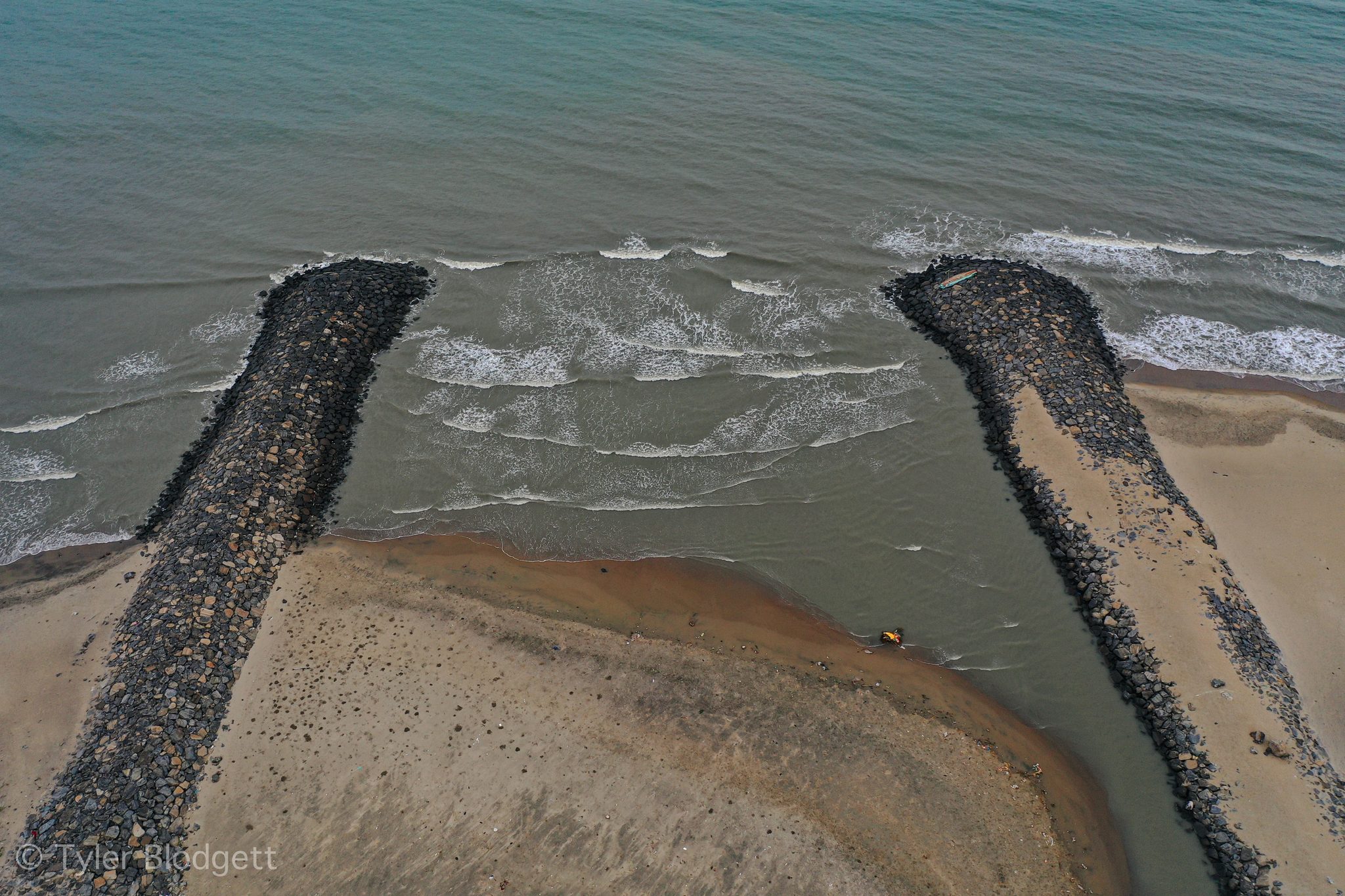 From above, two breakwaters guide the river into the sea.