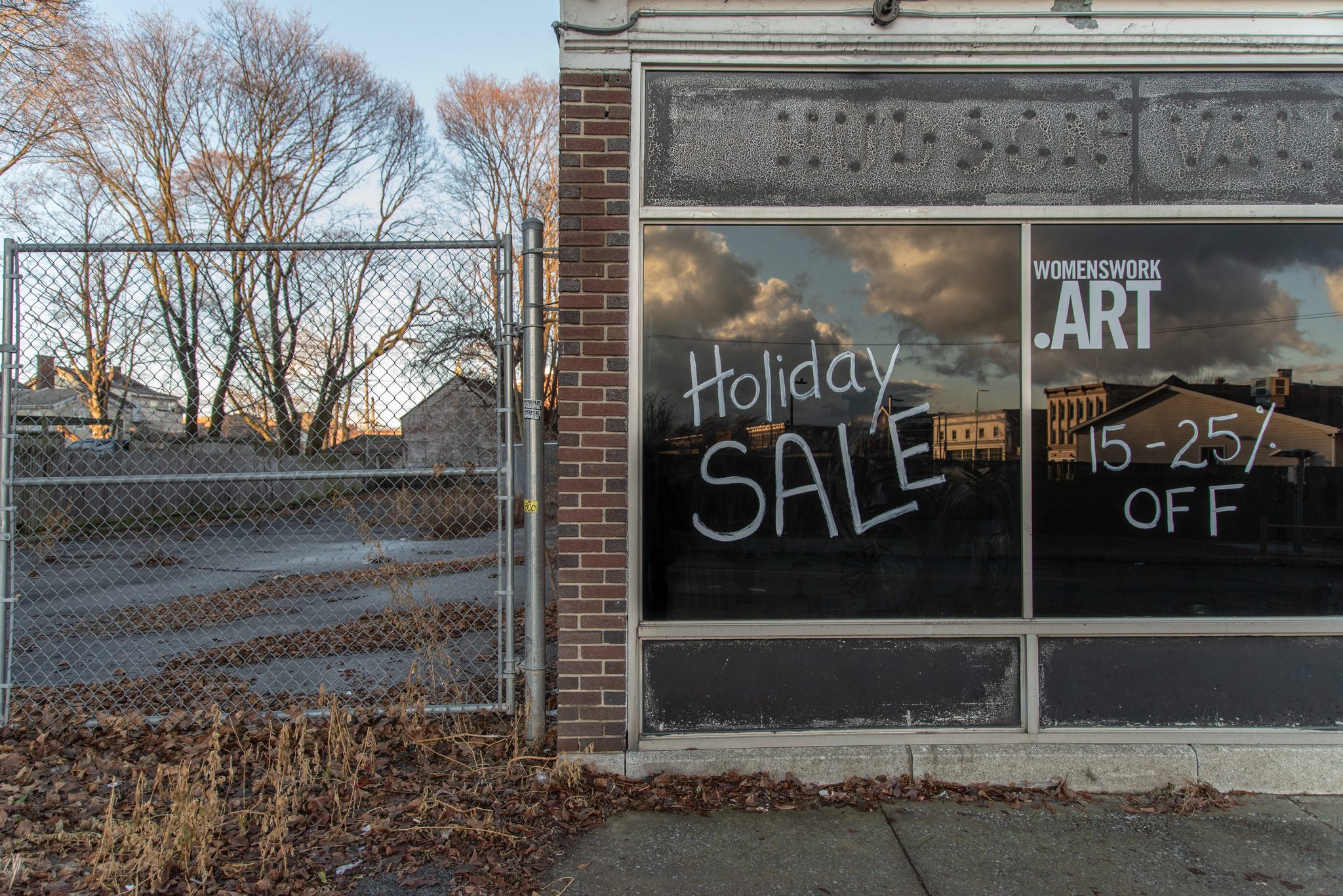 Holiday Sale, 15 to 25% off, chalked on a storefront window beside an empty lot.