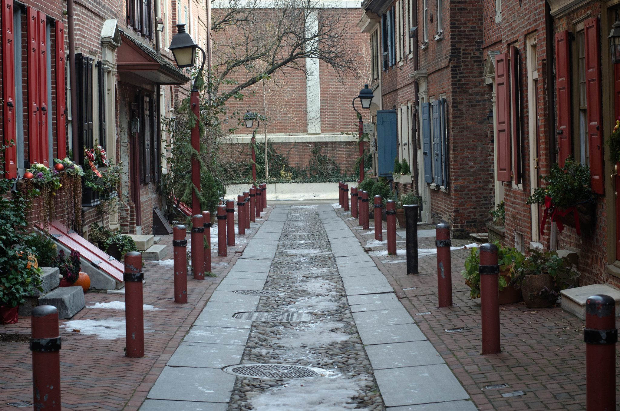 Elfreth's Alley runs narrow between brick row houses, shutters red and blue.
