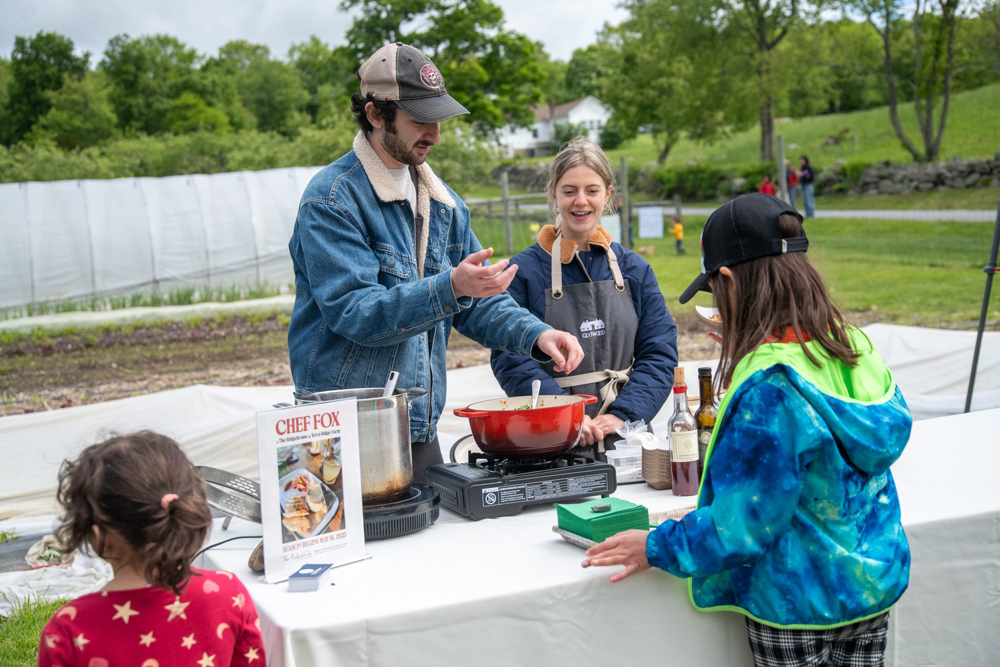 The cooks hand out tastes to the kids crowding the table.