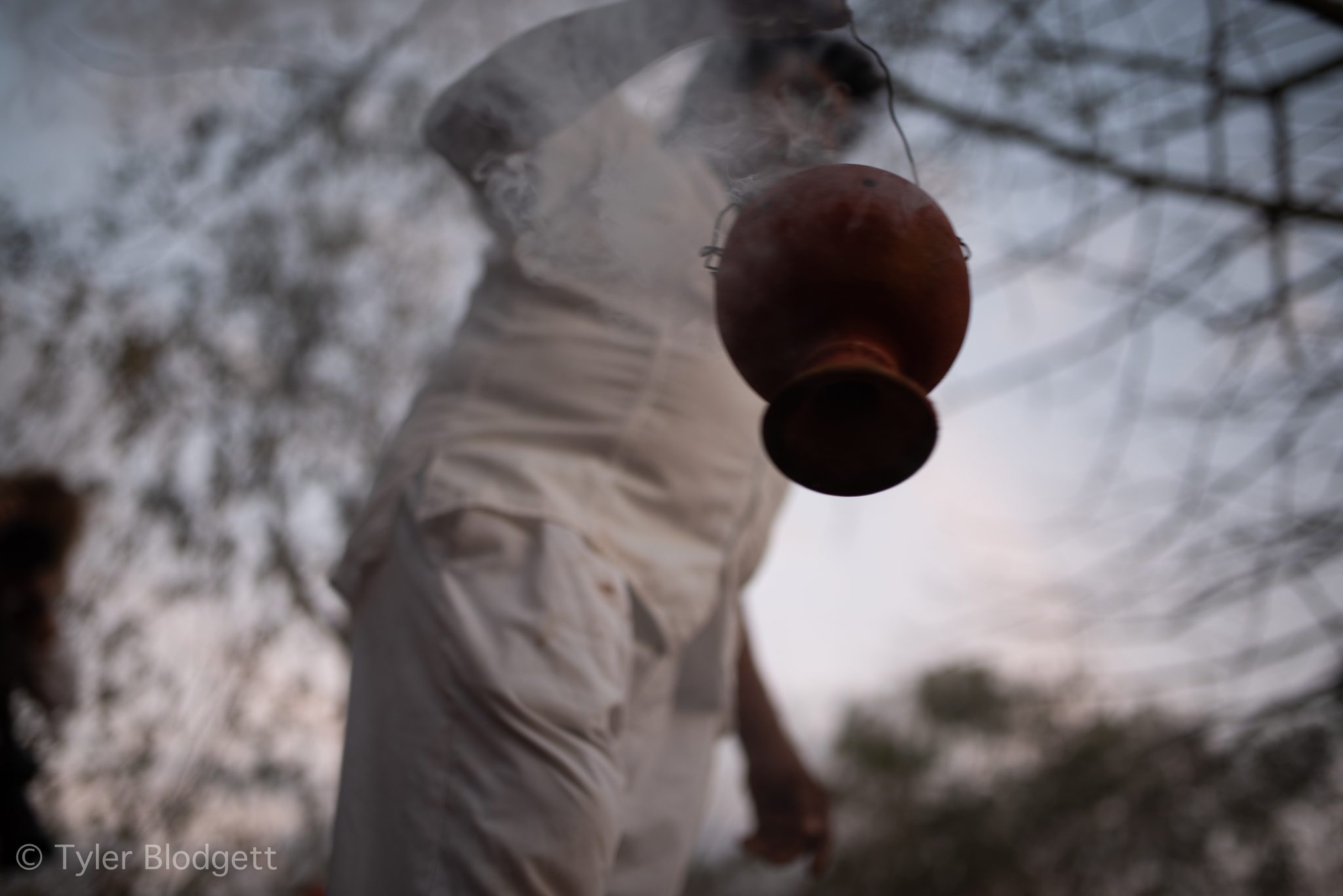 A clay censer swings from a cord, trailing smoke.