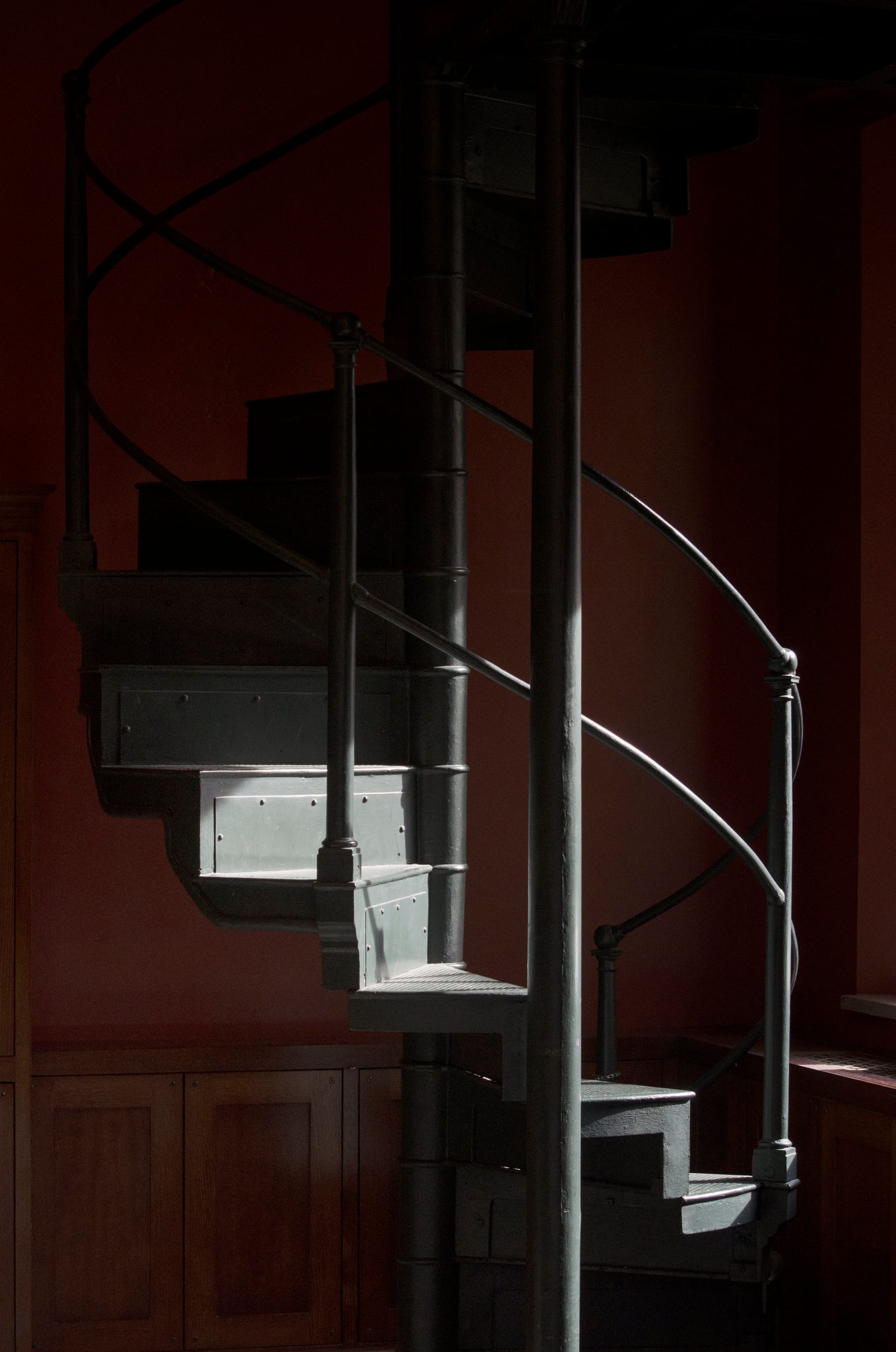 An iron spiral staircase curls up the red wall.
