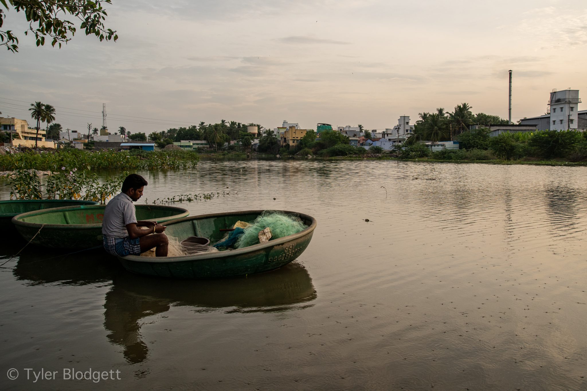A man sits in his coracle as the evening settles over the town's edge.