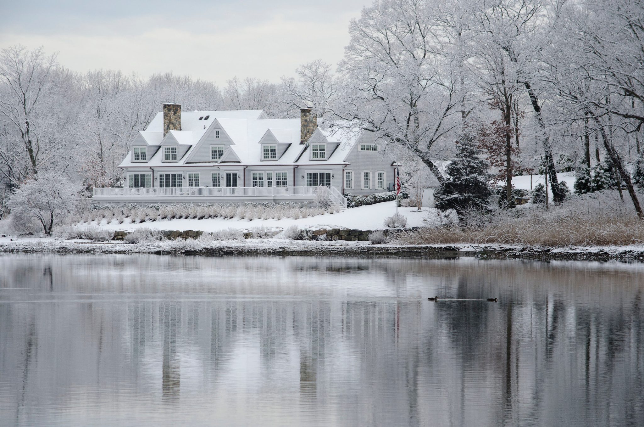Snow frosts every branch around the house across the water.