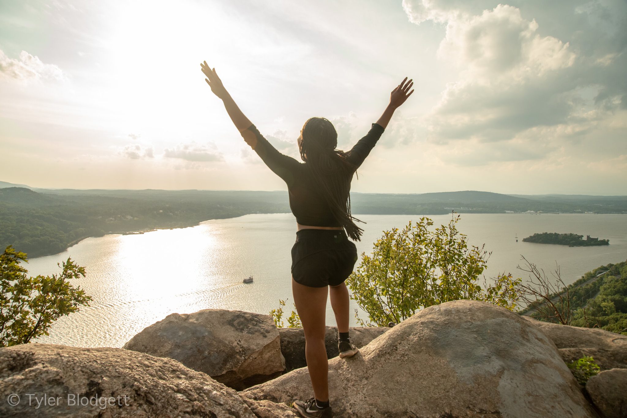 Arms up at the summit, she takes in the whole river at once.