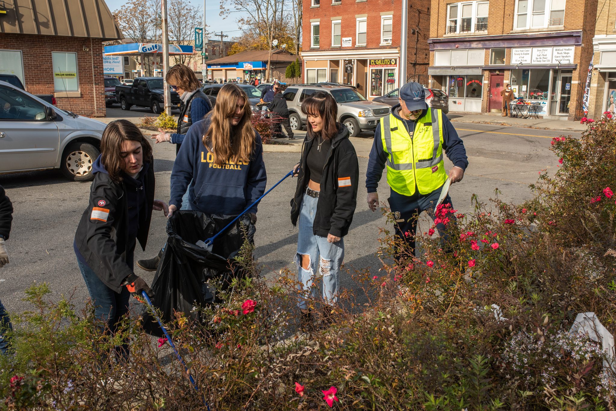 Students work the planters, pulling trash out from between the roses.
