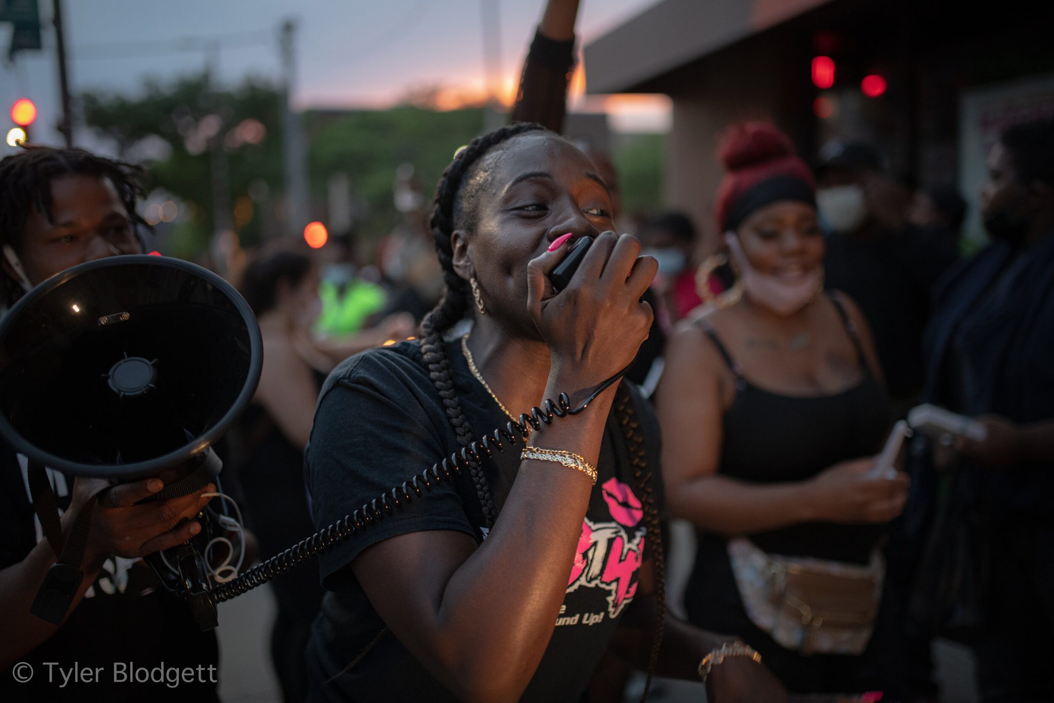 A woman leads the chant into the megaphone, the women beside her smiling.