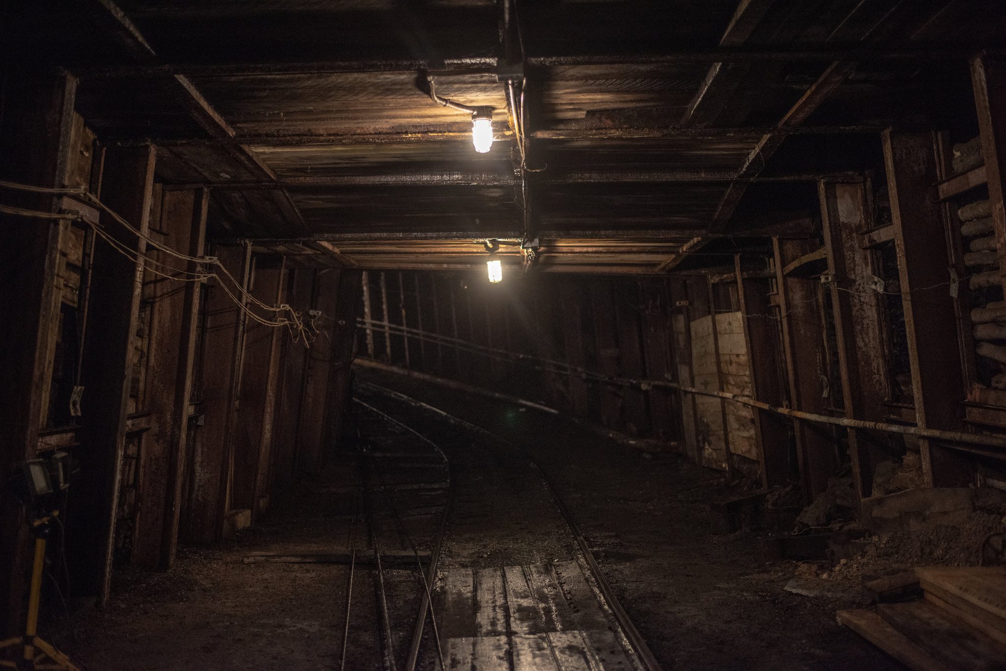 Timber posts shore up the ceiling of a long mine tunnel.