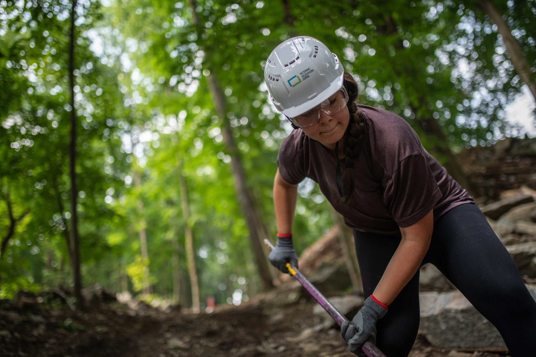 A crew member squints under her white helmet, bar in hand.