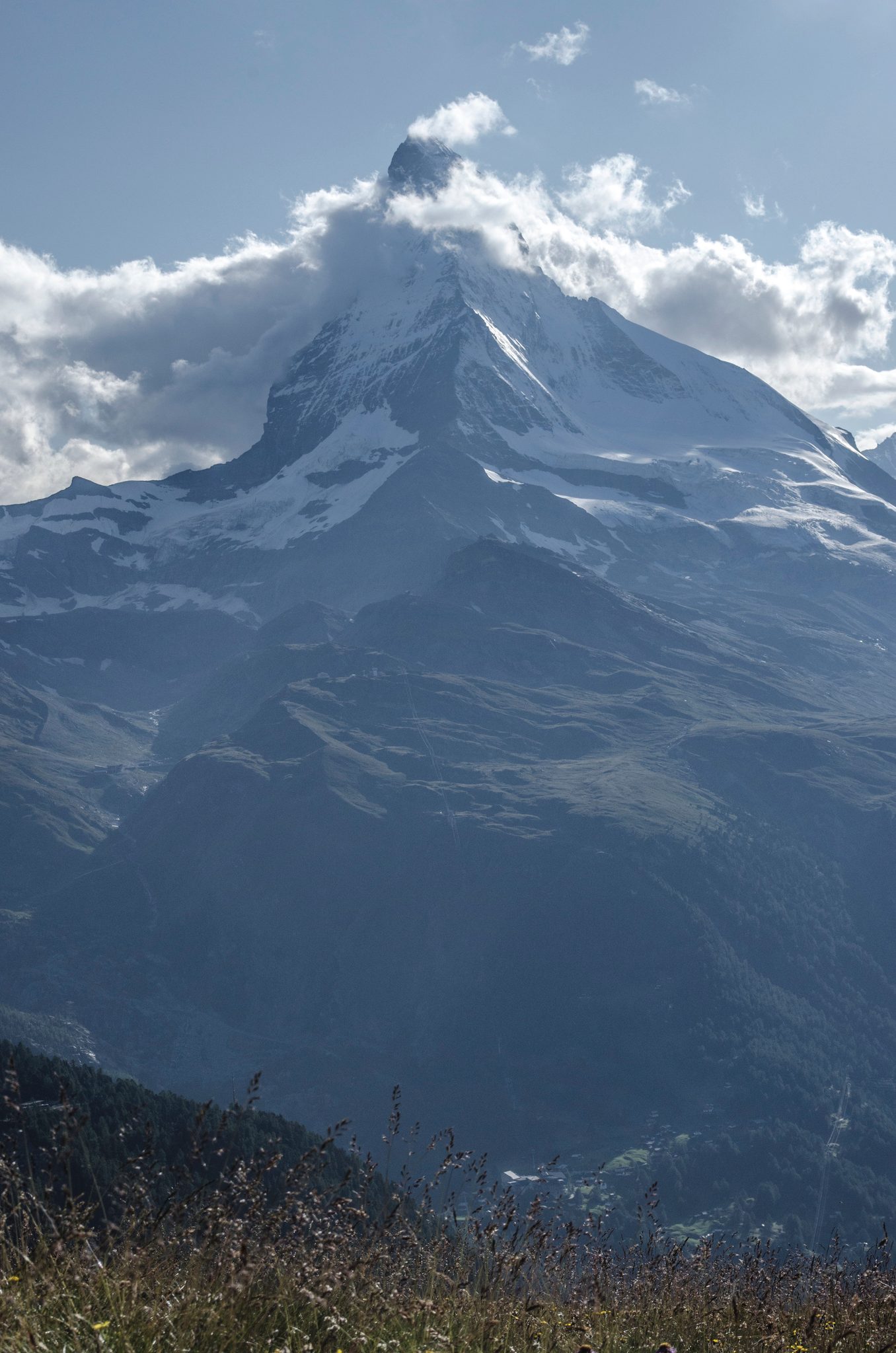 Clouds catch on the summit as the peak rises above the valley.