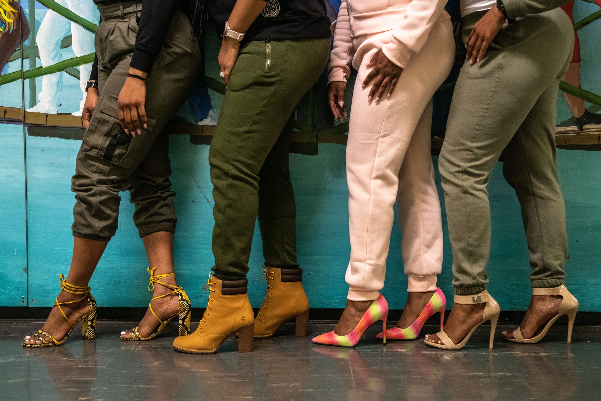 Heels, boots and sneakers lined up against the mural.