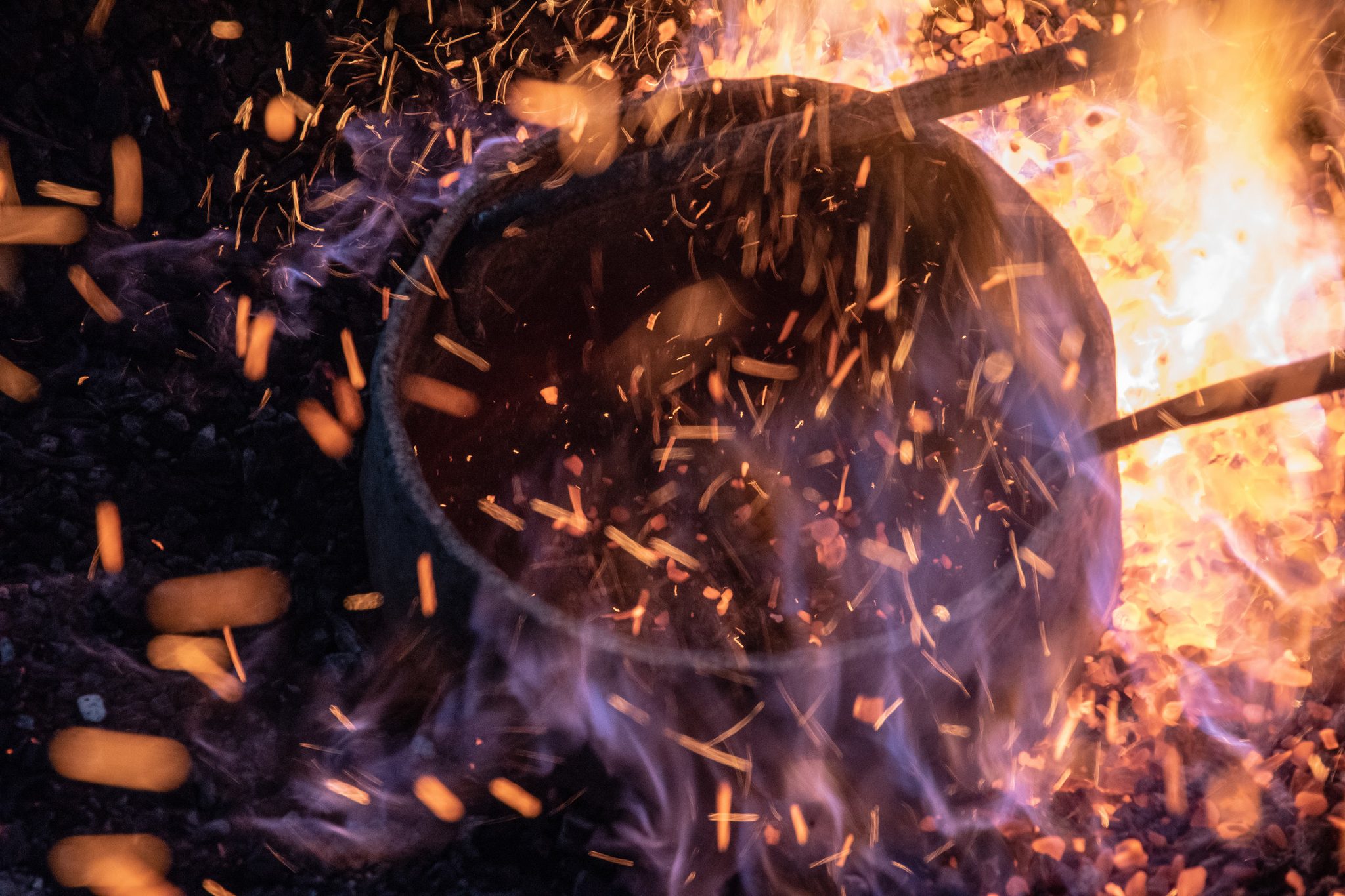 Sparks swarm around the crucible as the metal comes to heat.