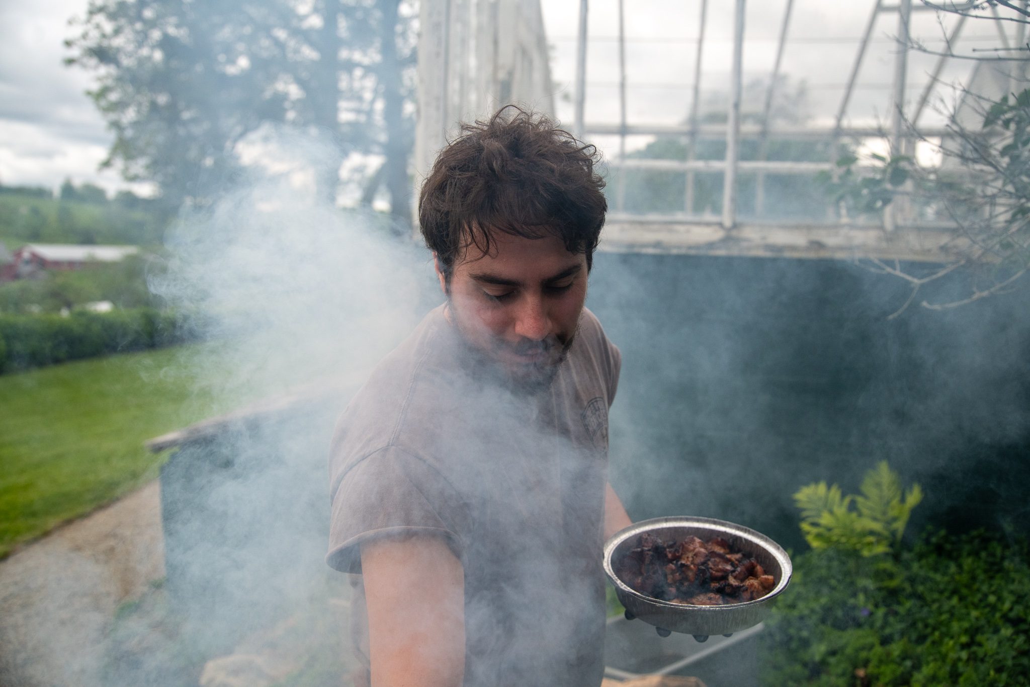 Smoke rolls up from the grill and swallows the cook whole.