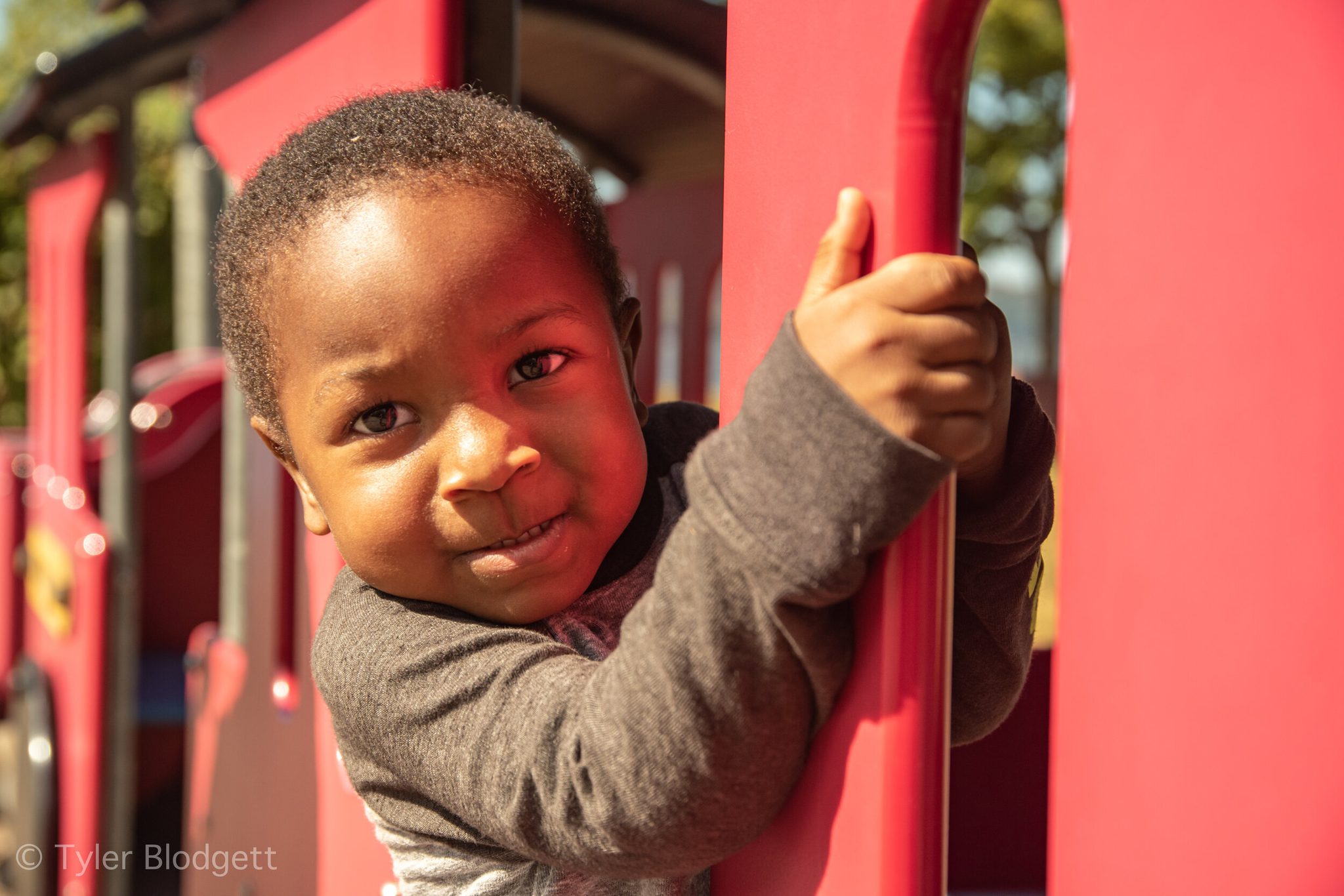 A small boy grips the pole and grins, not about to let go.