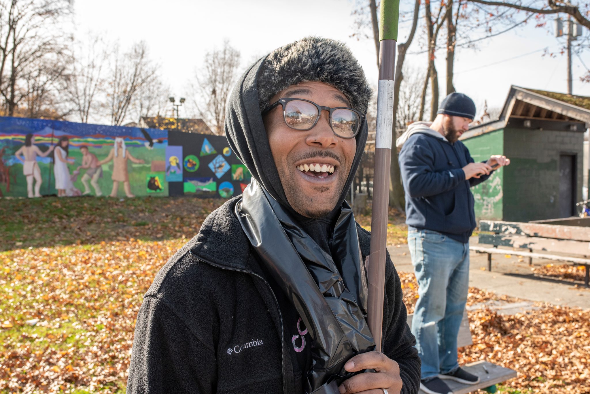 A laugh under a winter hood, rake in hand.
