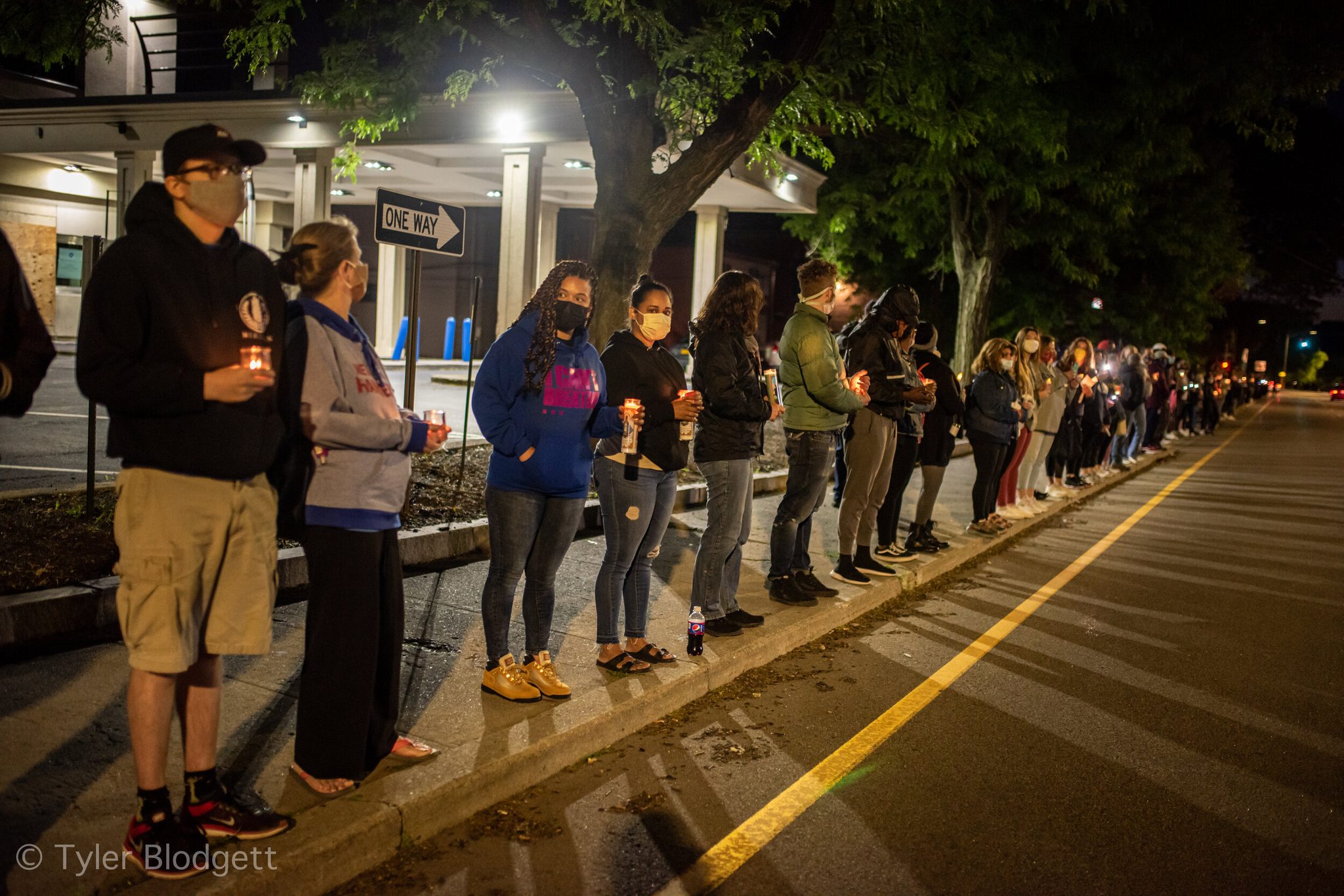 The line of candles runs down the curb as far as the eye can see.