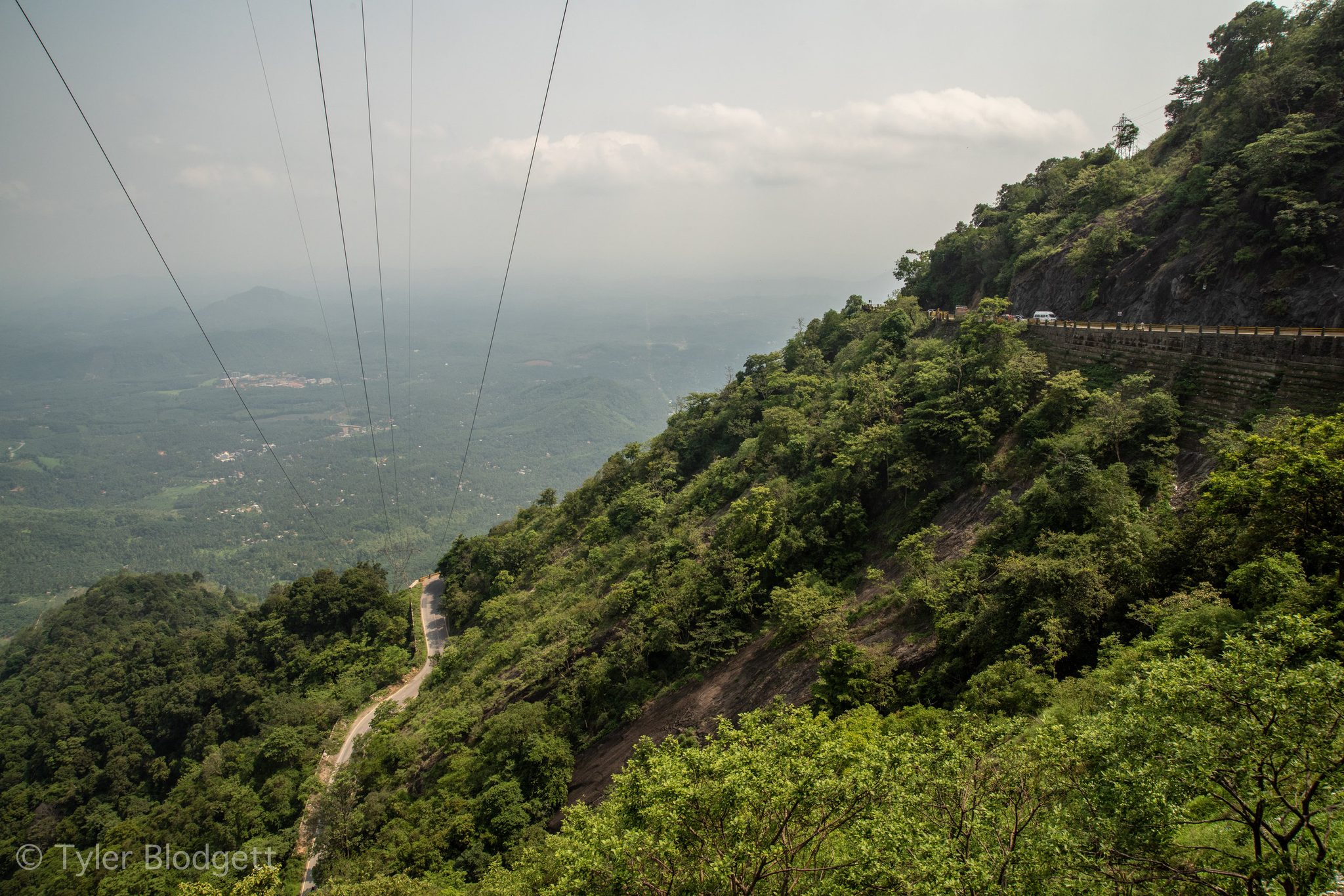 Power lines drop away down the mountainside toward the hazy plains.