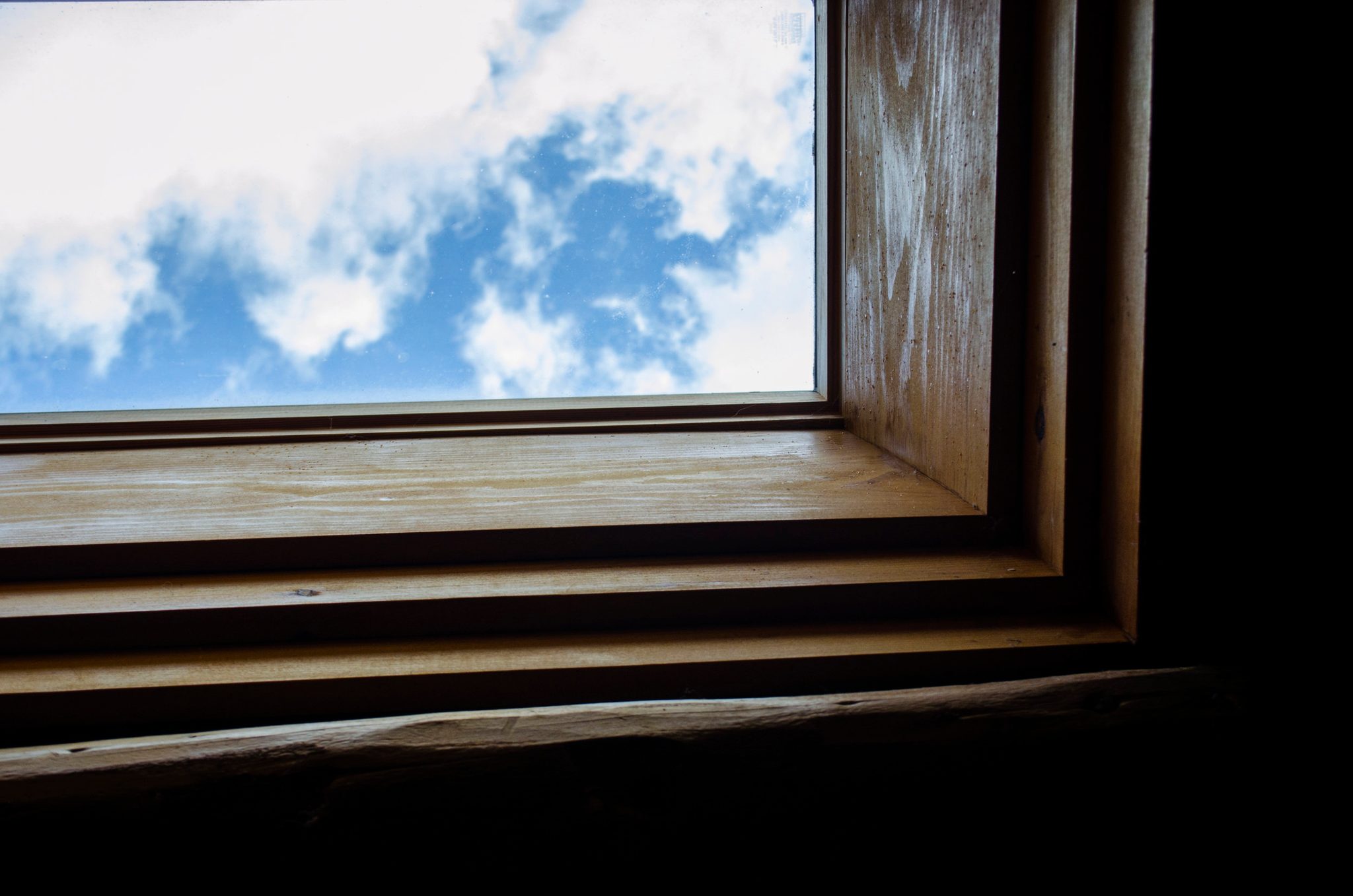 Blue sky and clouds through a cabin skylight. Looking up I saw blue sky and white, billowy clouds.