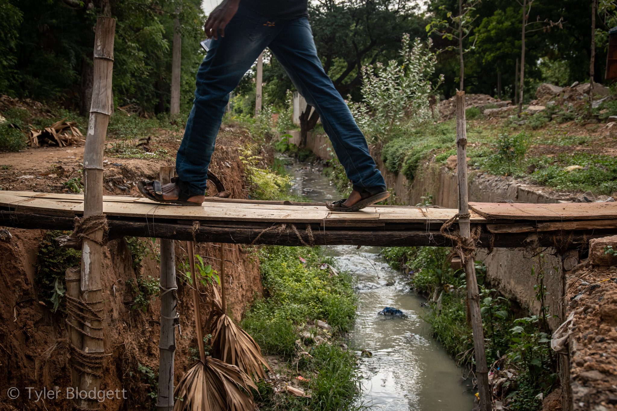 A man in jeans strides across the same narrow bridge.