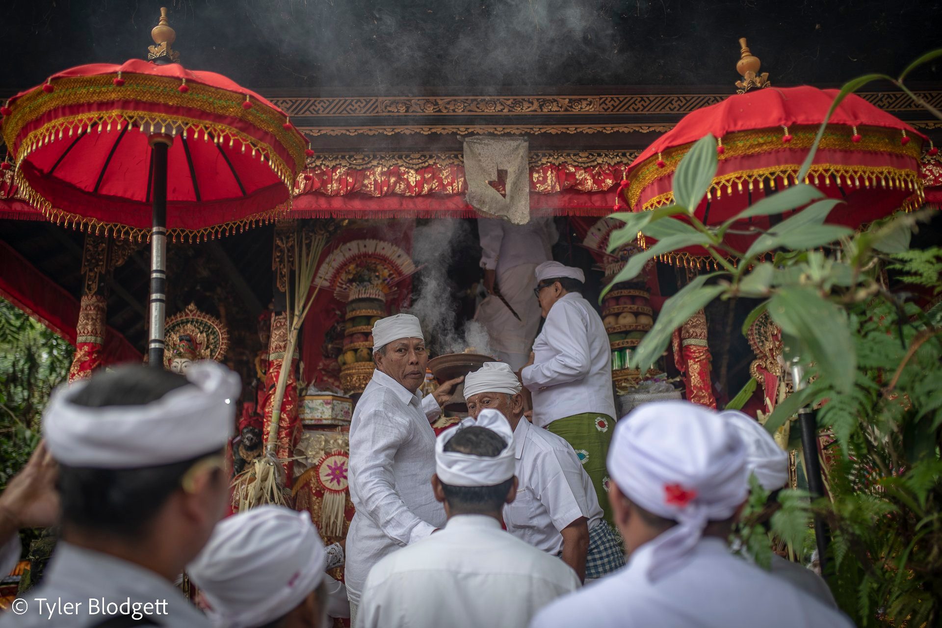 Smoke rises from the red and gold shrine as the priests tend the offerings inside.