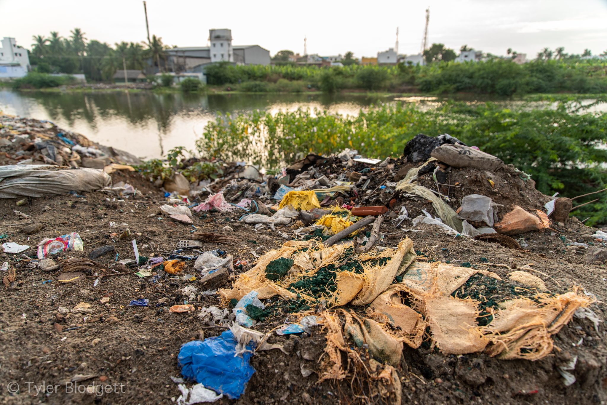 Rubbish spills down the bank to the water's edge.