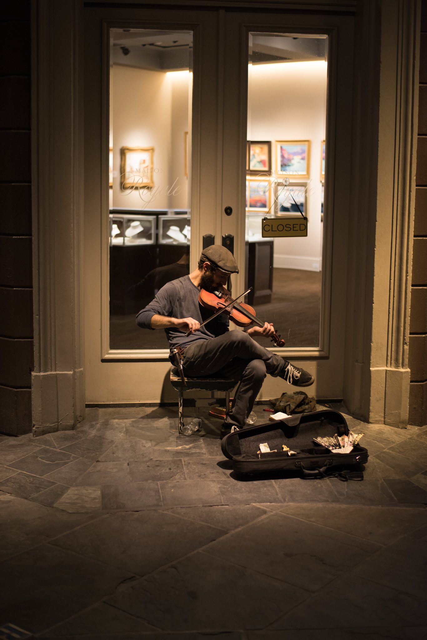A violinist plays in a gallery doorway on Royal Street, eyes closed. Filling the air with tender music for those few willing to listen.