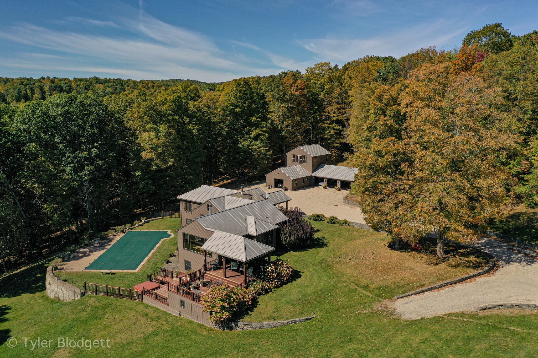 From above, the house settles into its clearing as the woods around it begin to turn.