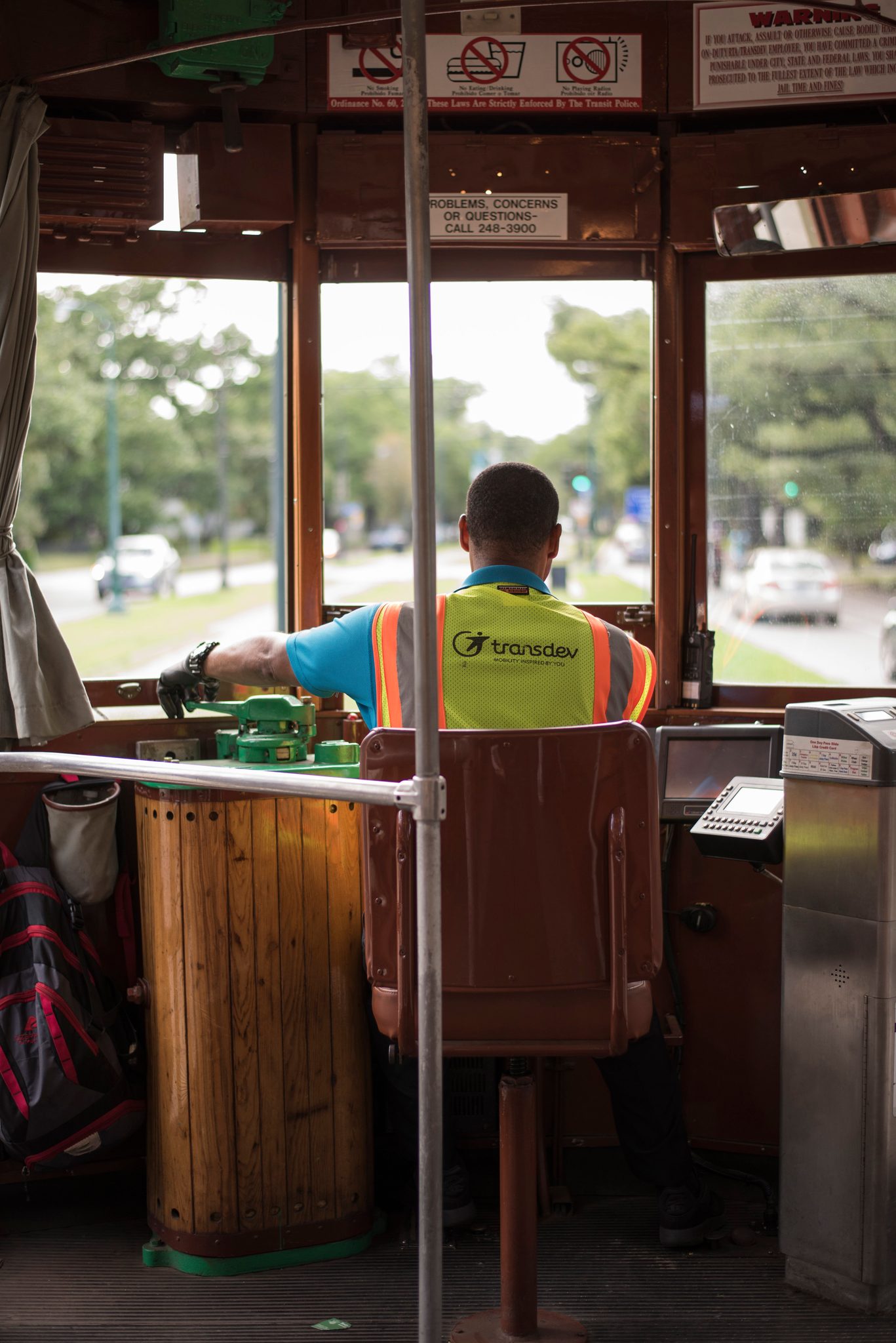The streetcar conductor at the controls, the green of St. Charles Avenue out the window.