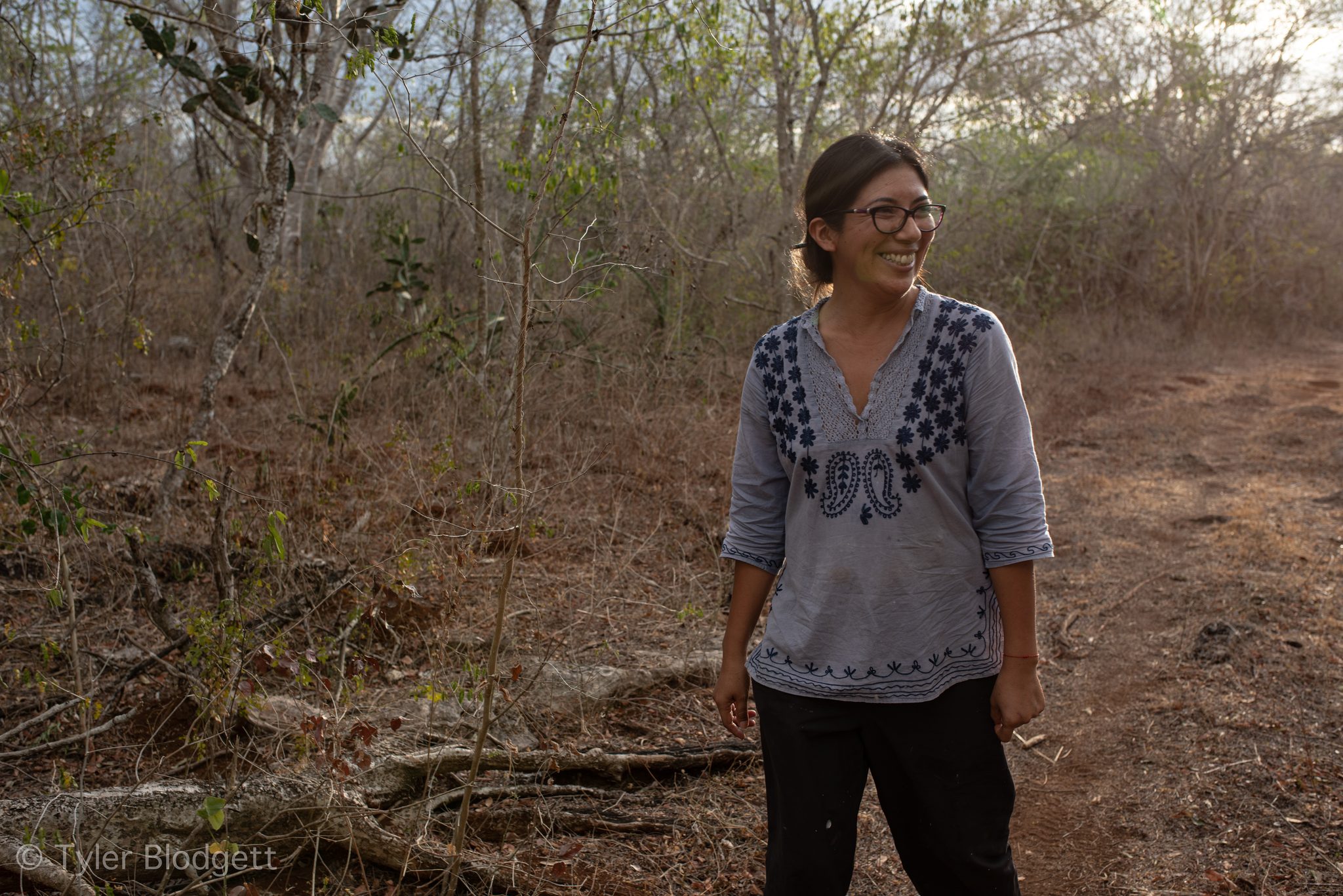 She stands smiling in the dry scrub as the light fades.