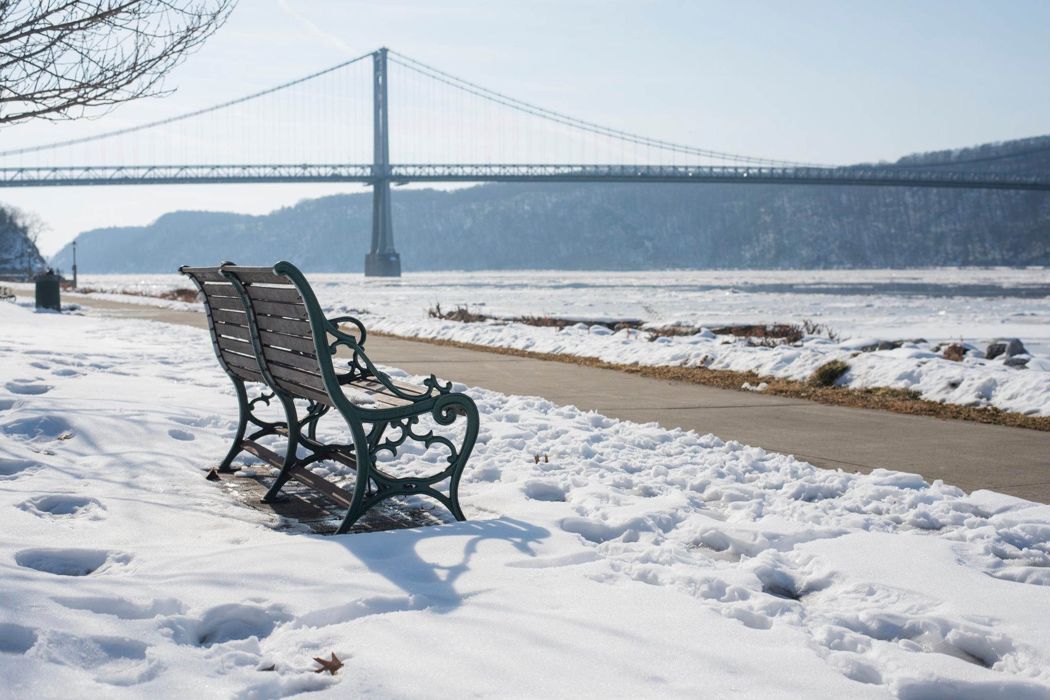 A bench waits in the snow beside the river. We all have one, a place that has borne the weight our hearts amass.