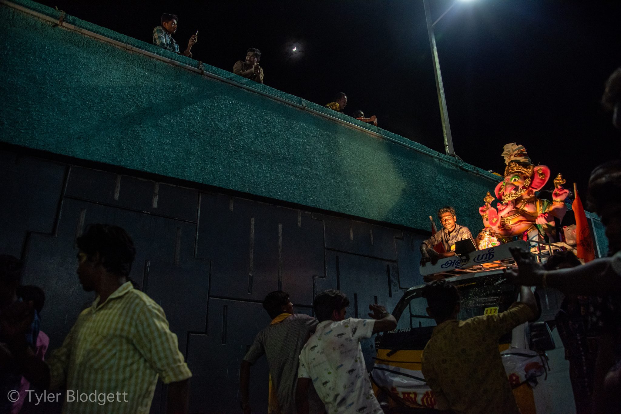 Faces turn toward the glowing idol as the procession moves along the wall.