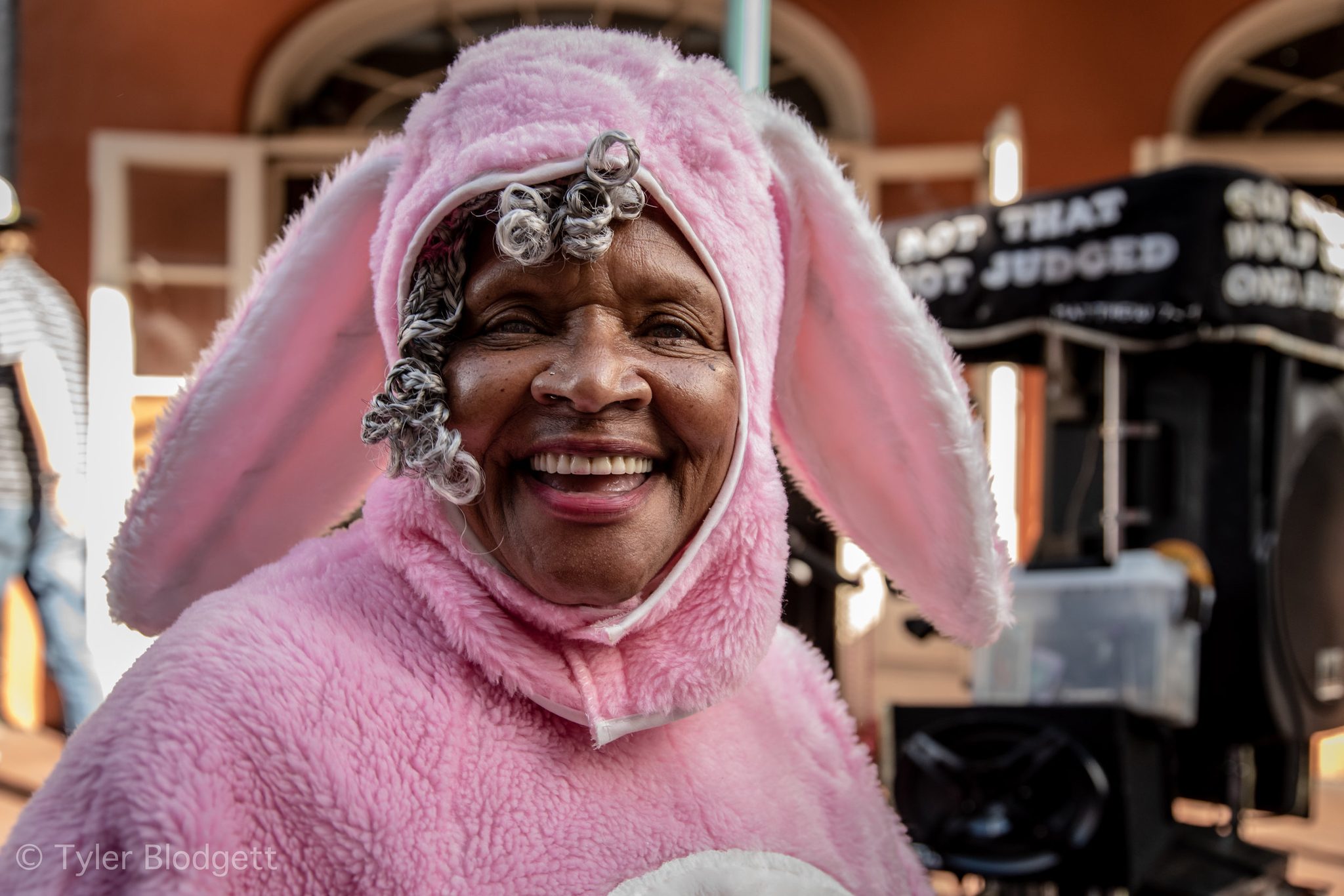 A woman in a pink bunny suit beams at the camera, curlers peeking out.