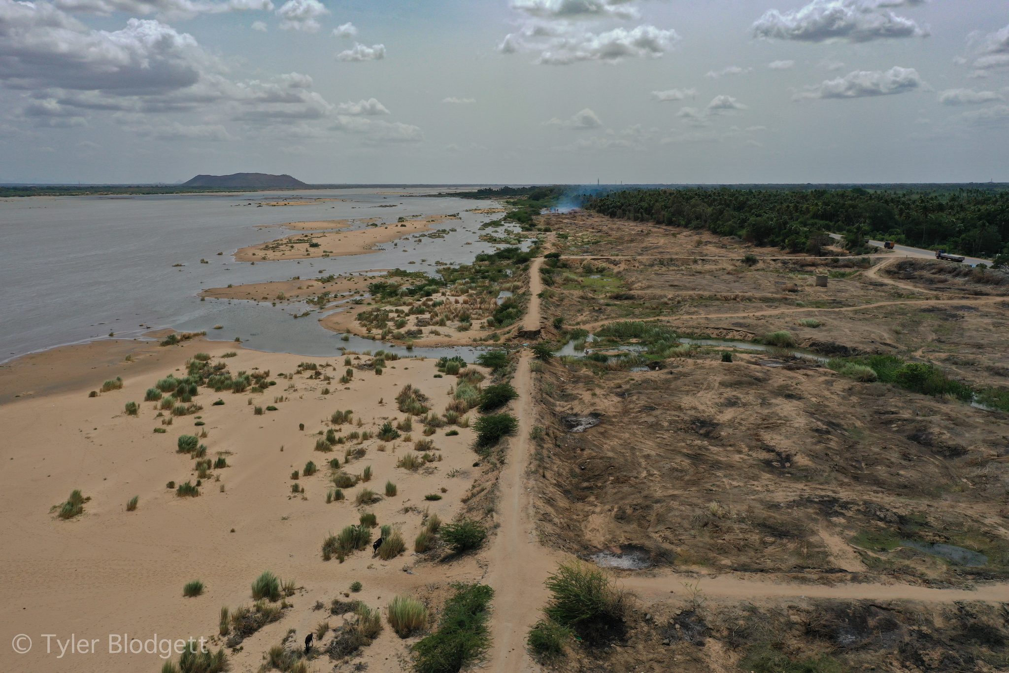 The river runs thin between wide banks of sand and scrub.