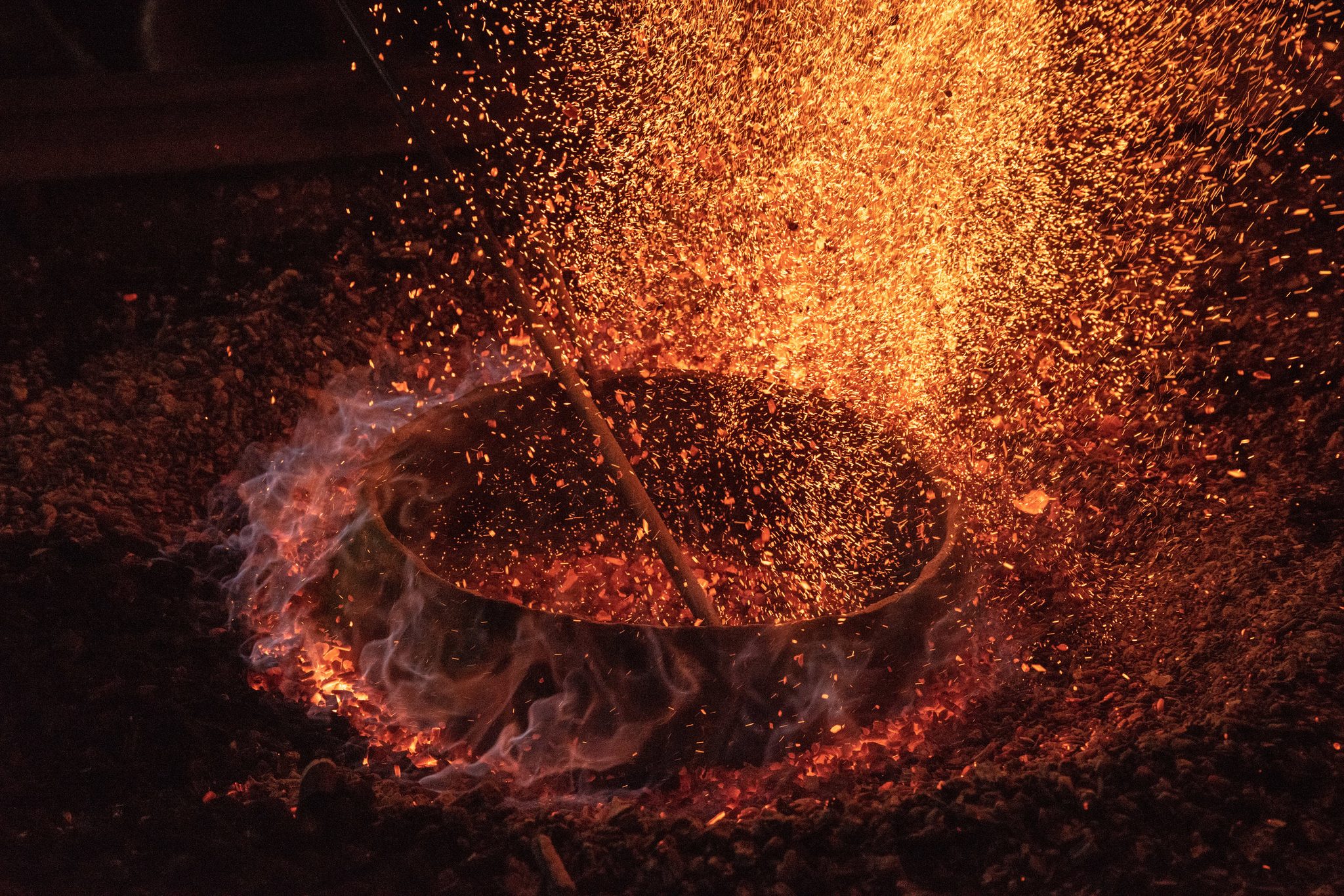 Blue flame rings the crucible and the sparks rise in a wall of gold.