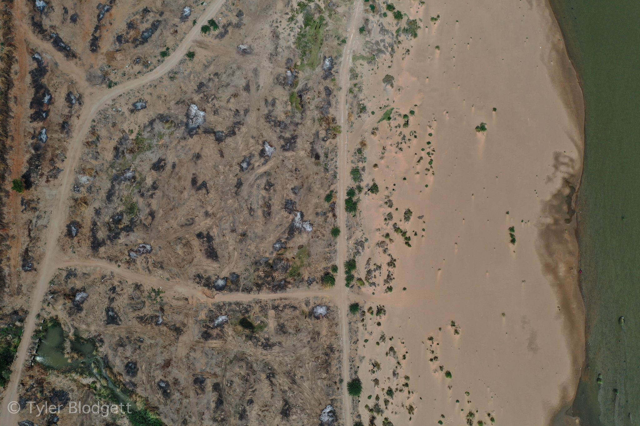 Tracks crisscross a sandy stretch of the riverbed, seen from above.