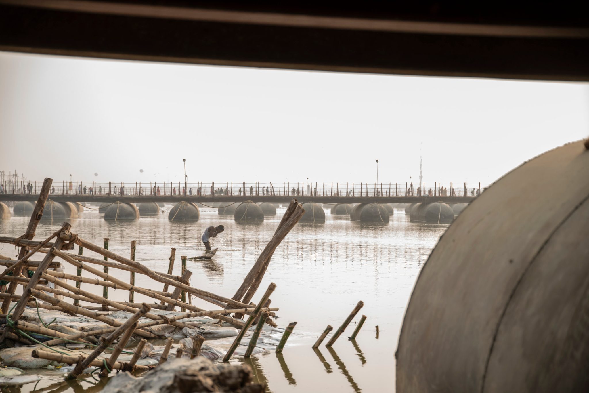 Man bathes in the Ganges between two of the temporary bridges built to allow passage