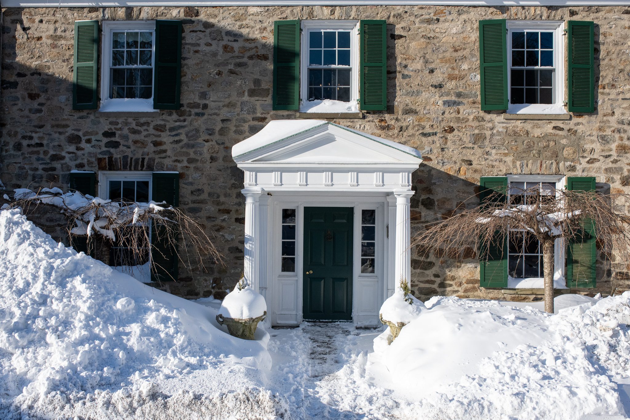 Snow banked against the stone house, right up to the white portico.