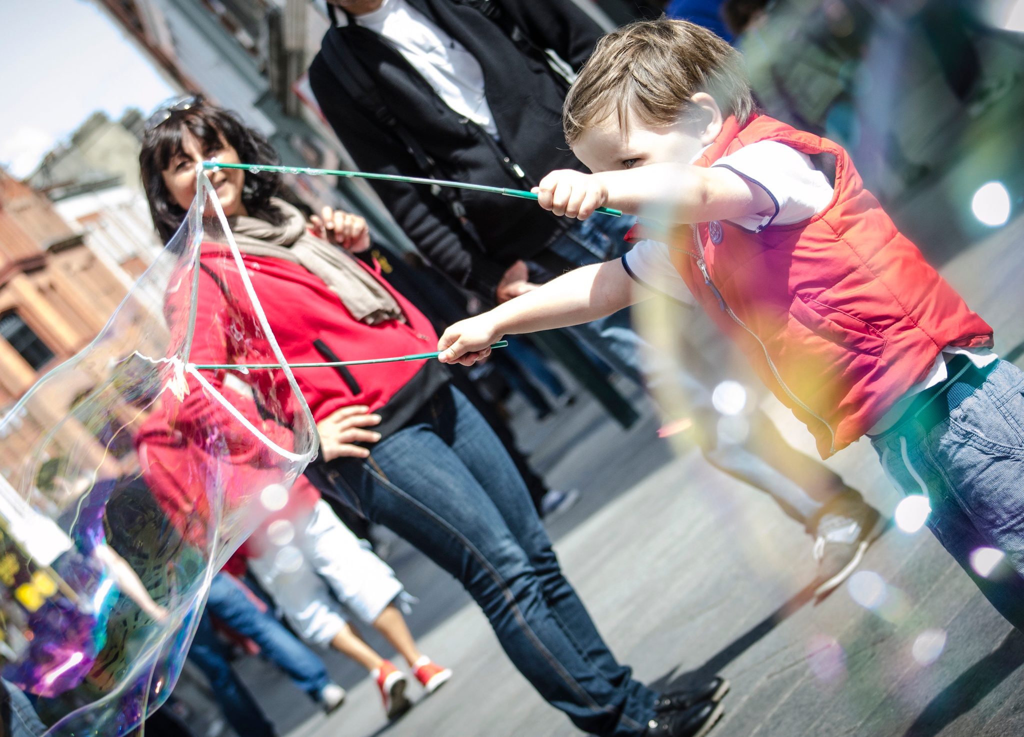 A boy chases a giant soap bubble down the busy street.