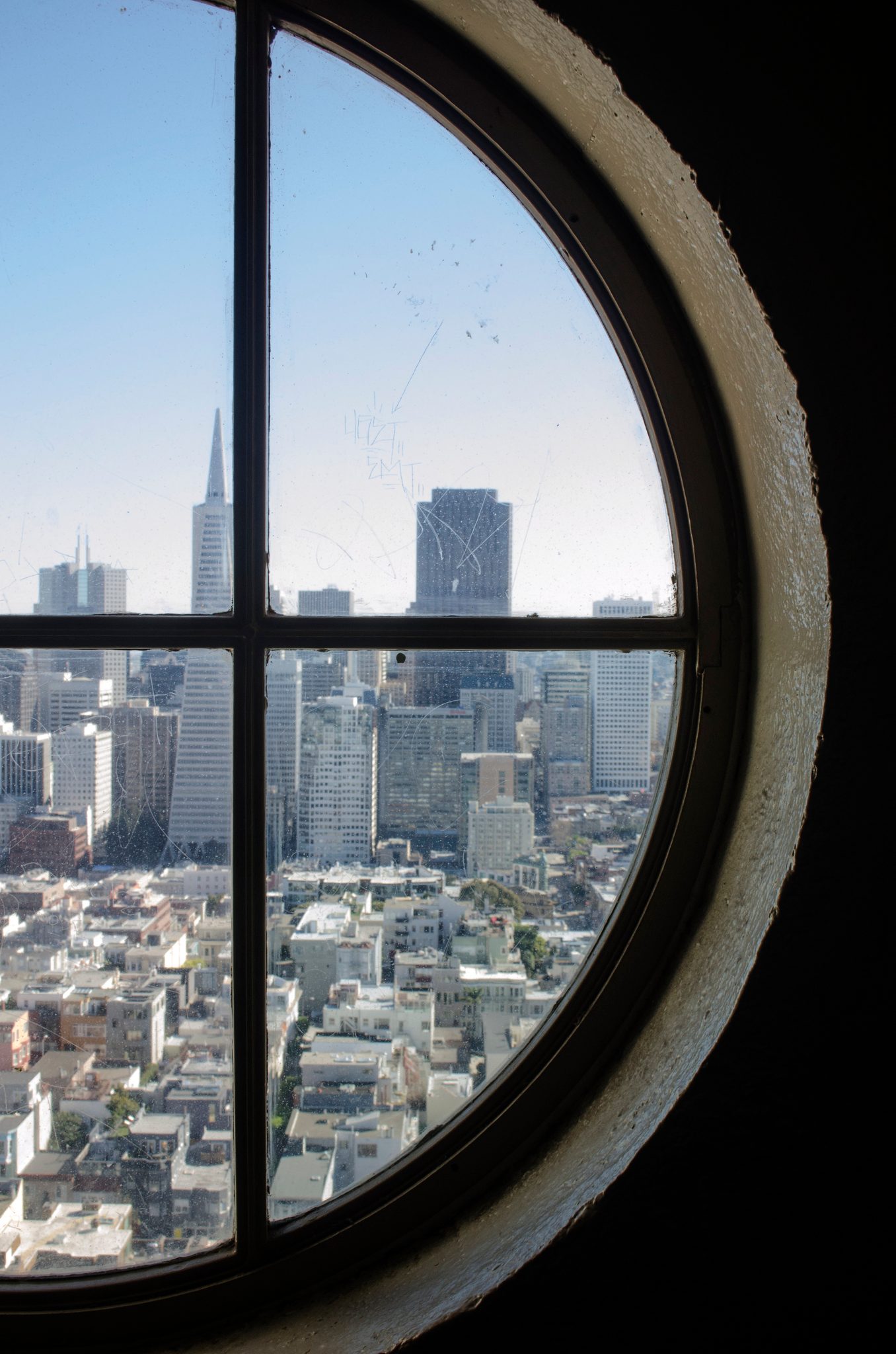 San Francisco's towers through a round window, the Transamerica spire at its center.