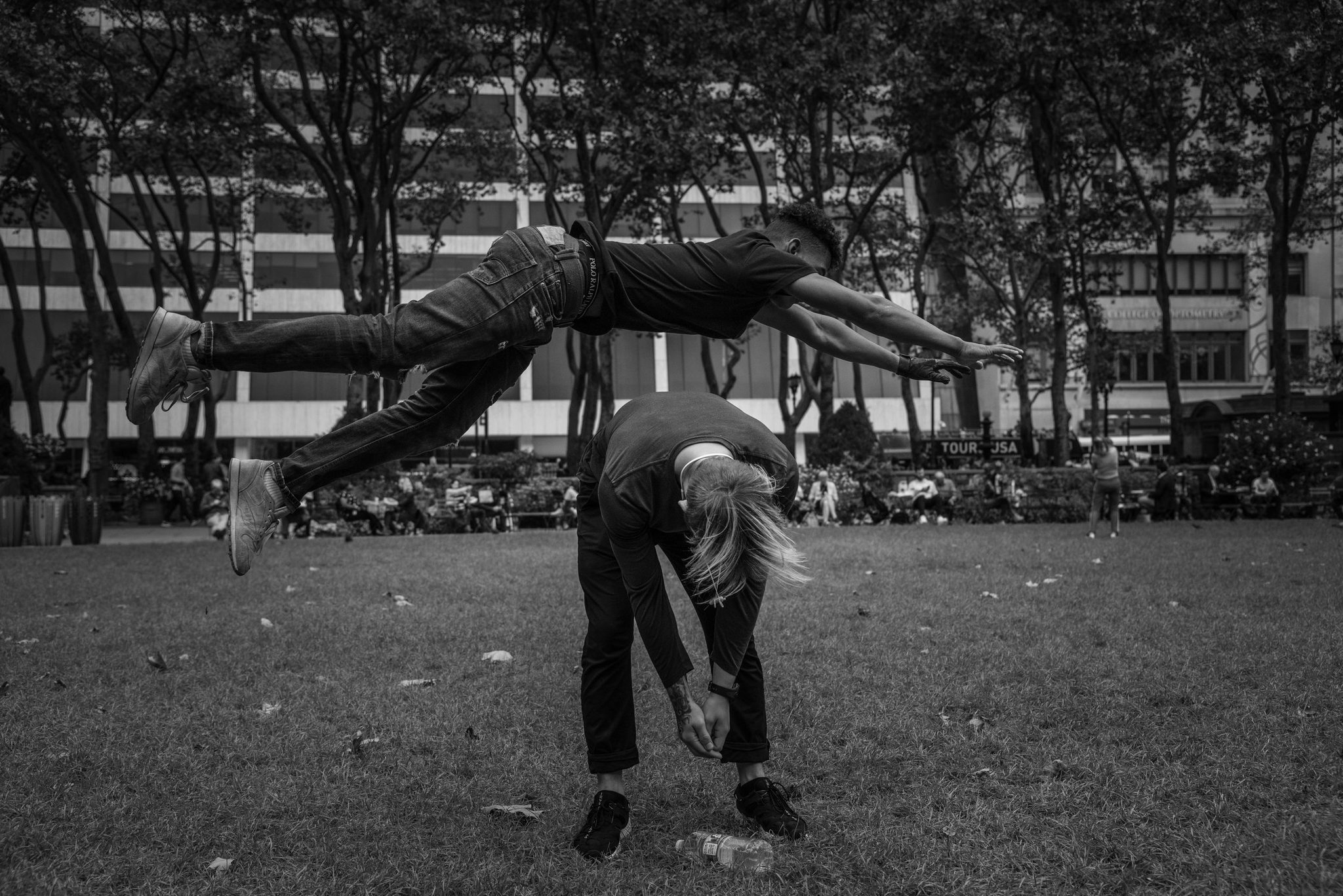 A grown-up game of leapfrog, one man sailing clean over another on the lawn.
