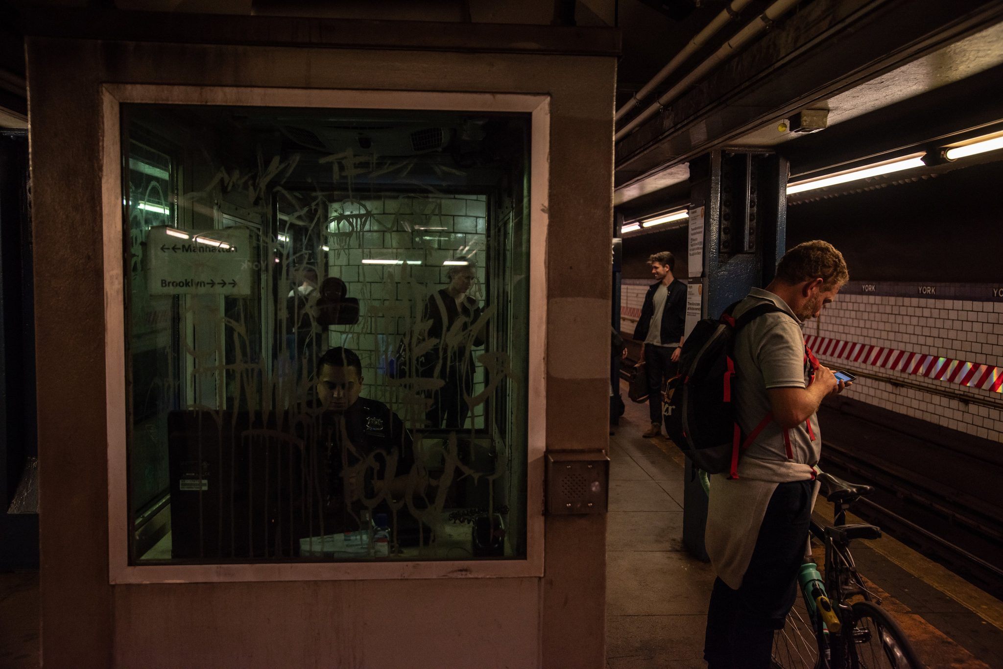 A cyclist checks his phone on the platform beside the old token booth.
