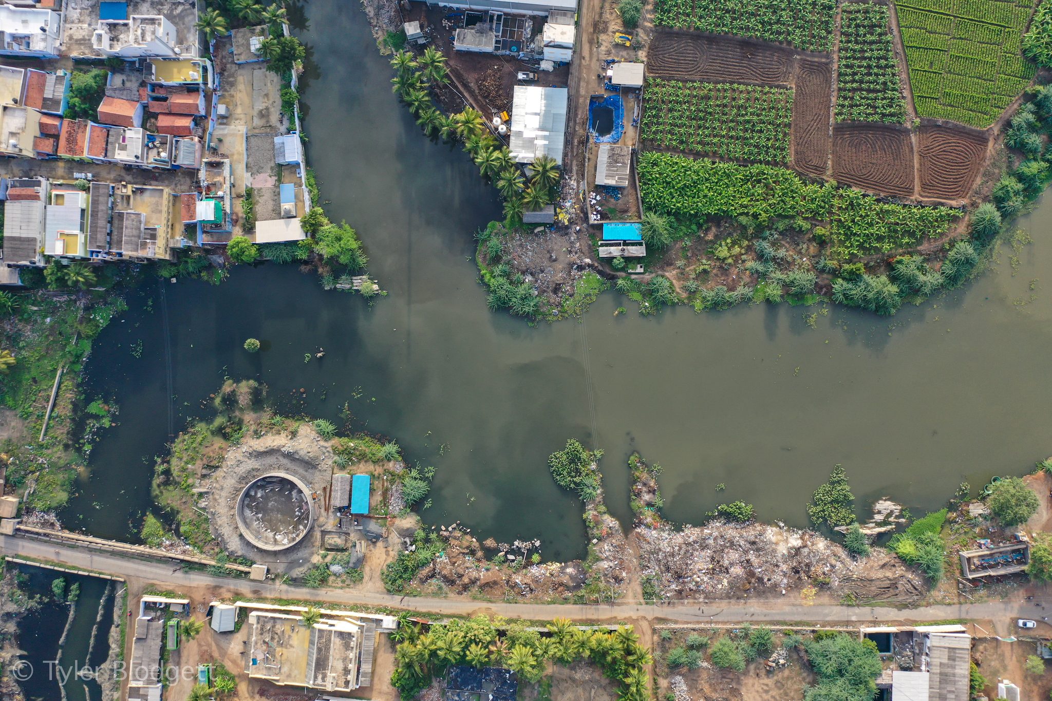 A town presses against the river, a circular pit on the far bank.