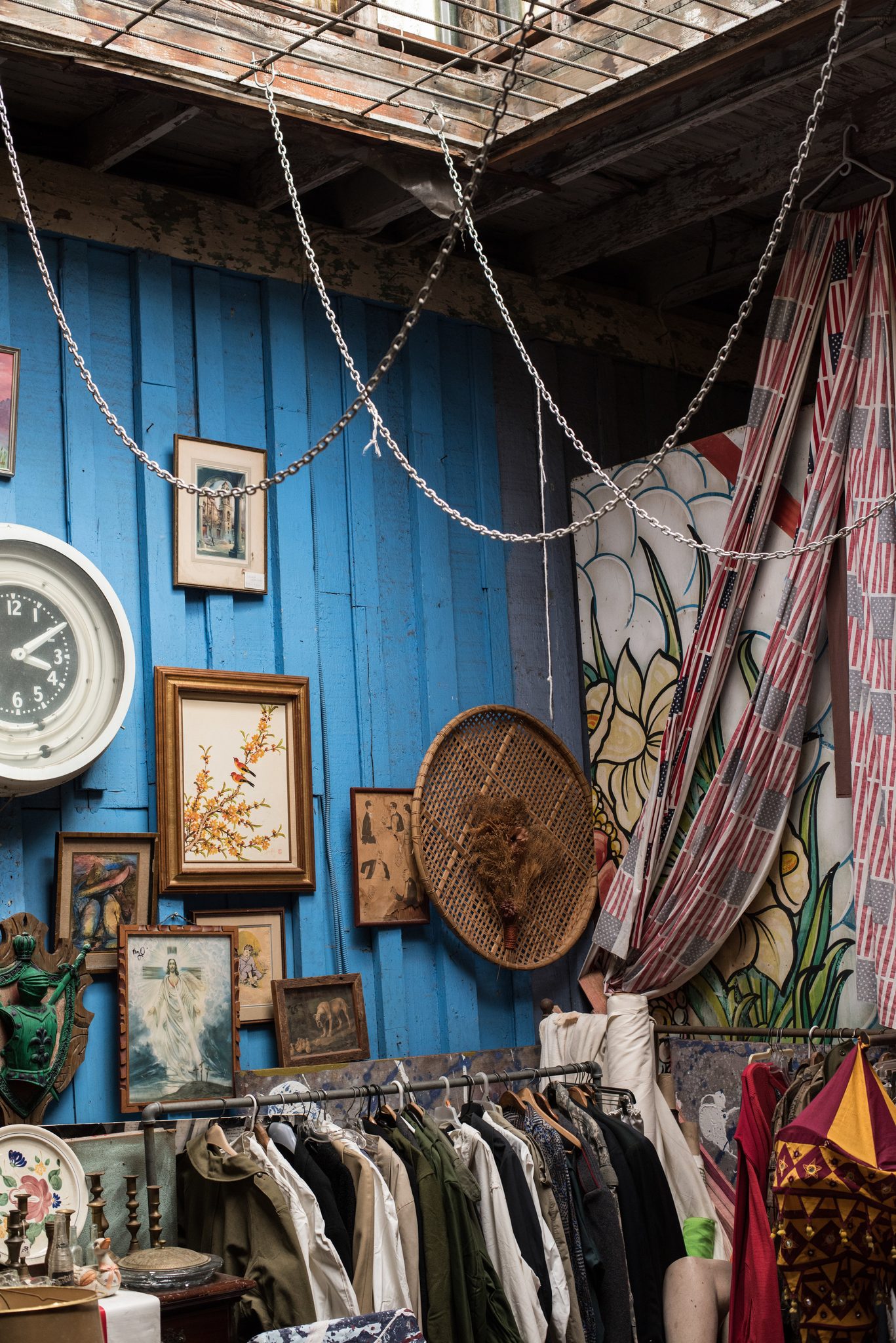 Chains, clocks and framed pictures crowd the walls of a thrift shop courtyard.