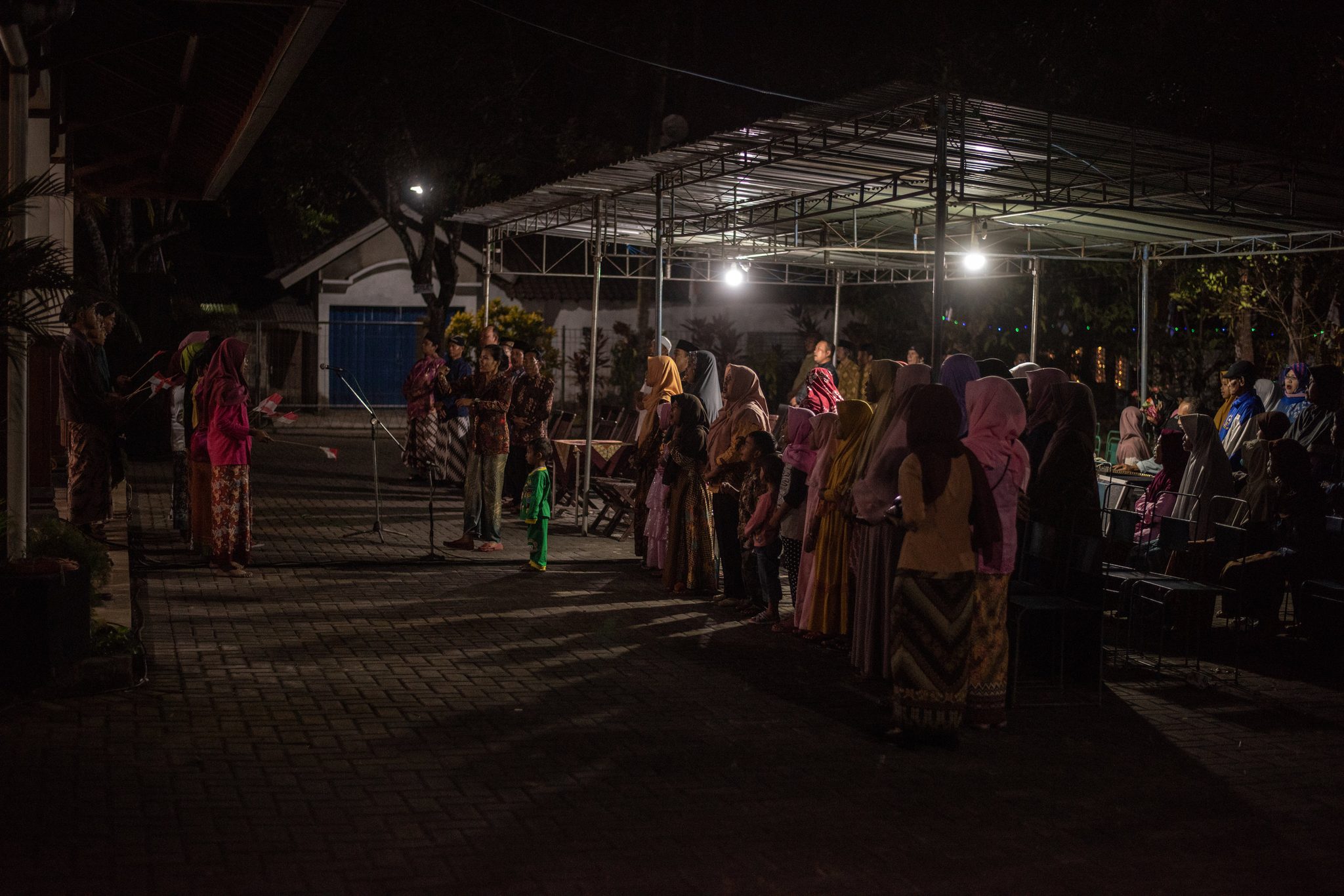 Women gather in the lamplit courtyard as the night's performance draws them in.