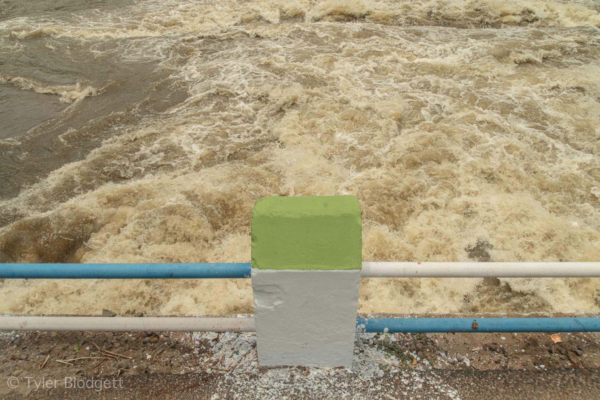 Brown floodwater surges past the railing.