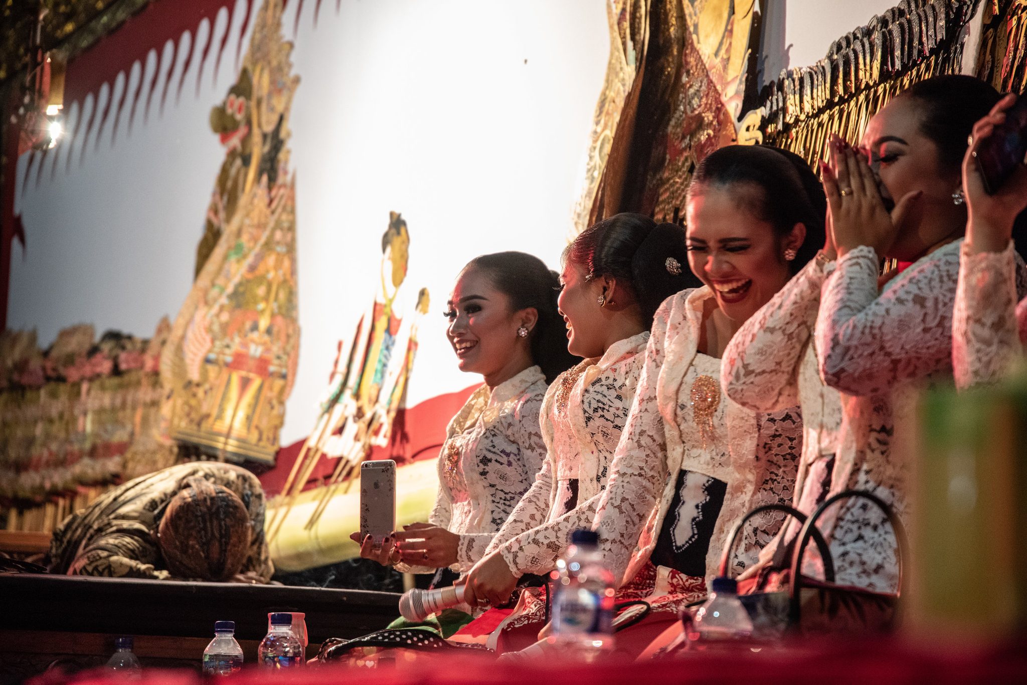 The singers dissolve into laughter, hands over their mouths.