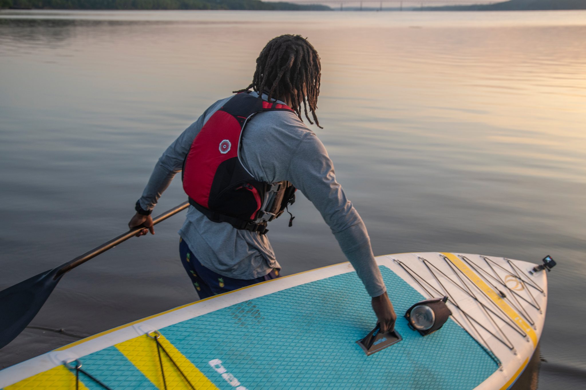 Paddle in one hand, Chev eases the board onto flat water at the shoreline.